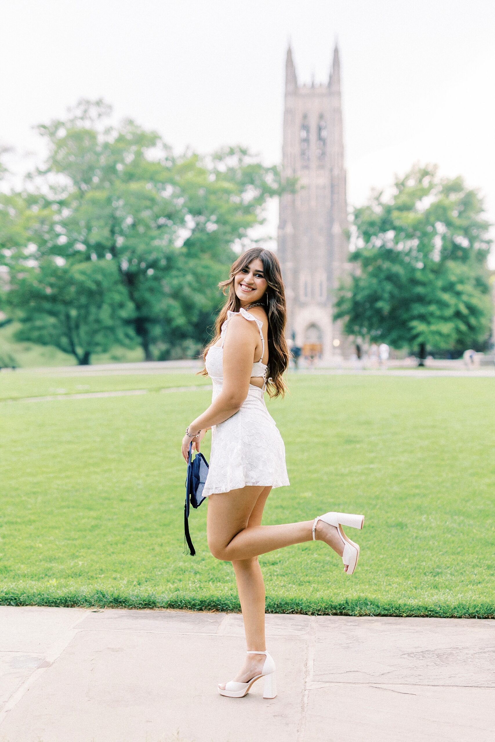 college senior stands with heel popped in front of Bell Tower at Duke