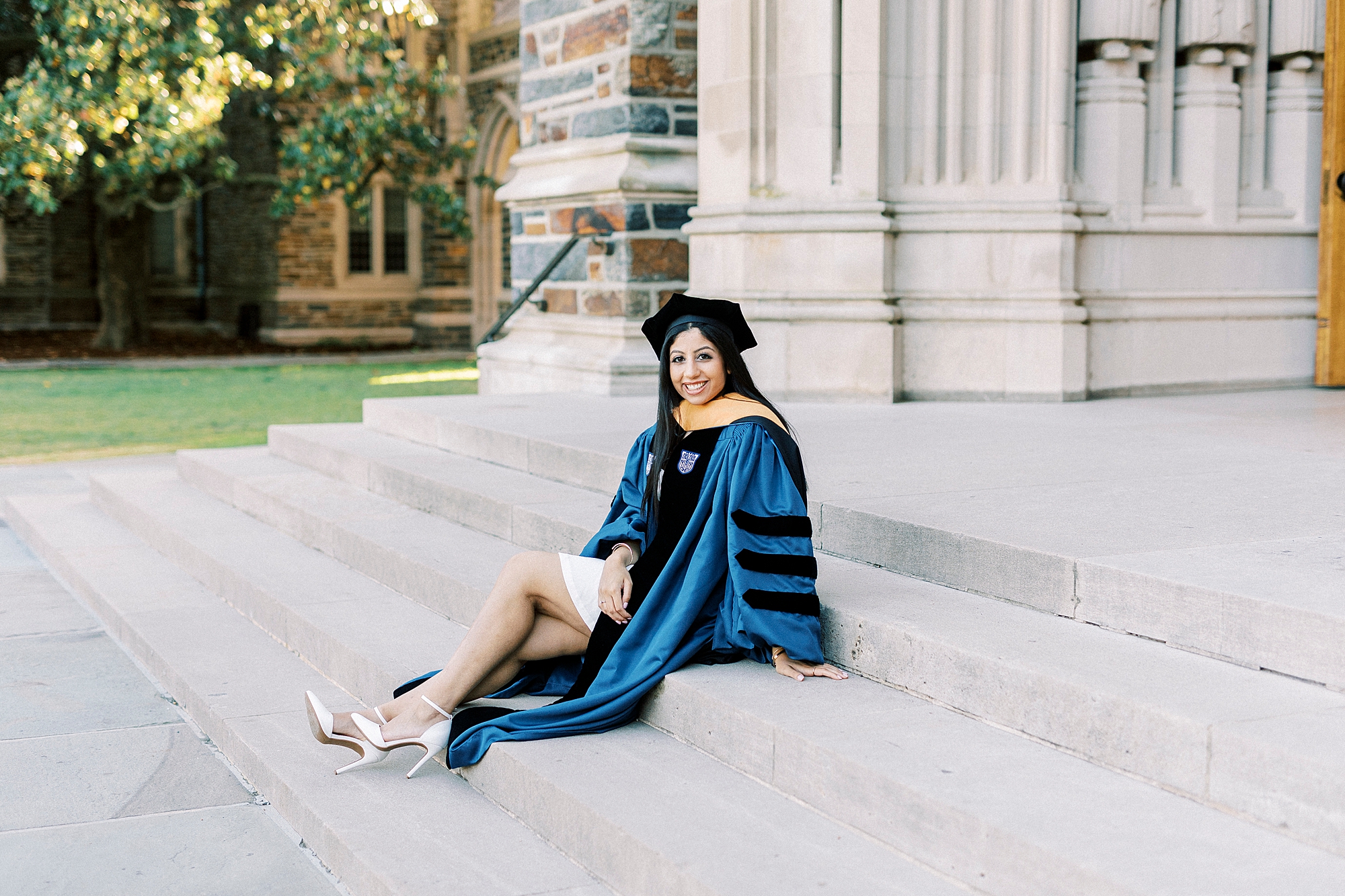 woman sits on steps of Duke Chapel during graduation portraits at Duke University