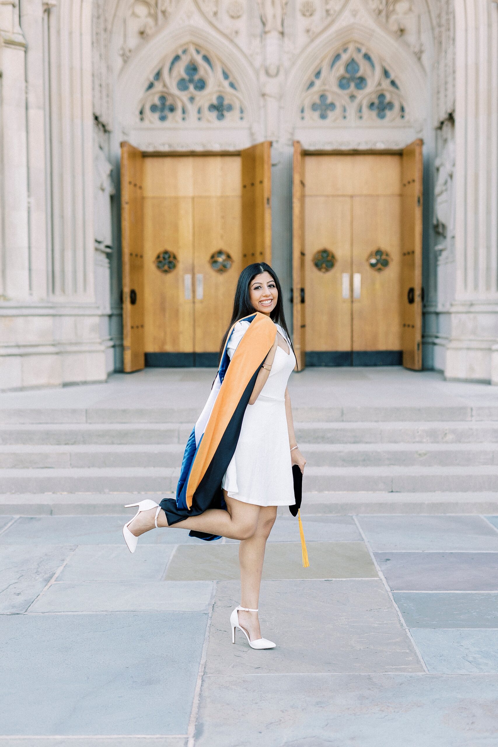 woman poses in front of wooden doors during graduation portraits at Duke University