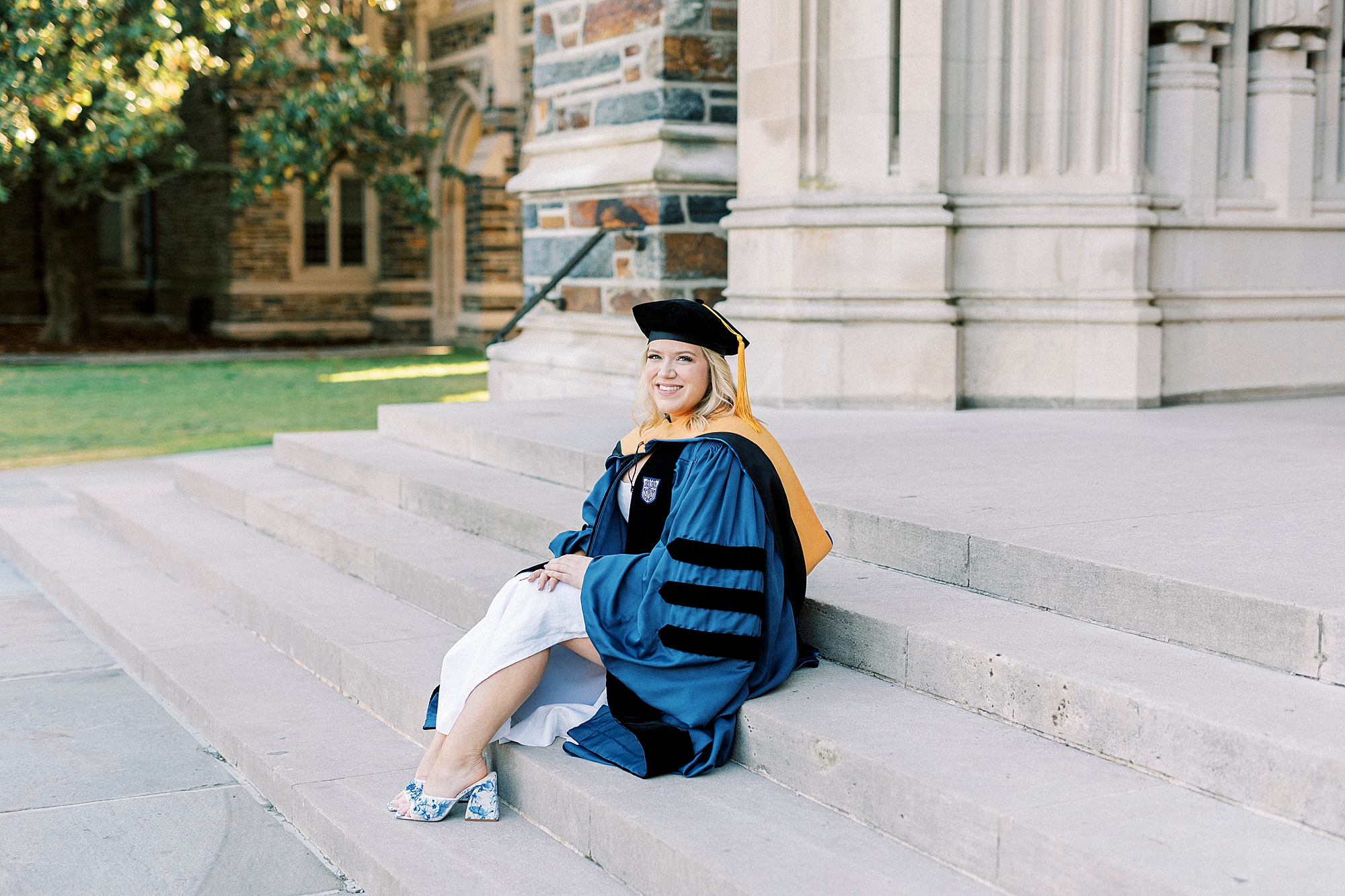 graduate sits on steps of chapel during graduation portraits at Duke University