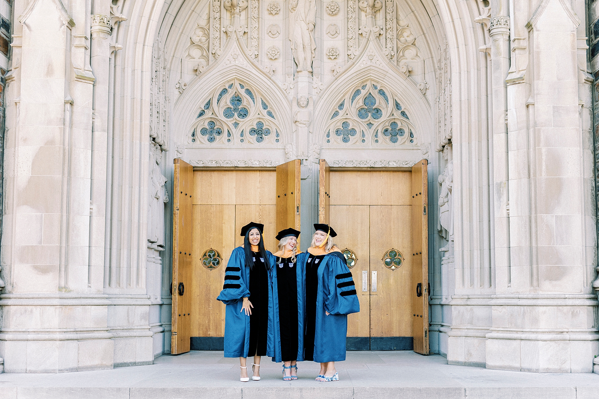 three women stand in front of wooden door during graduation portraits at Duke University