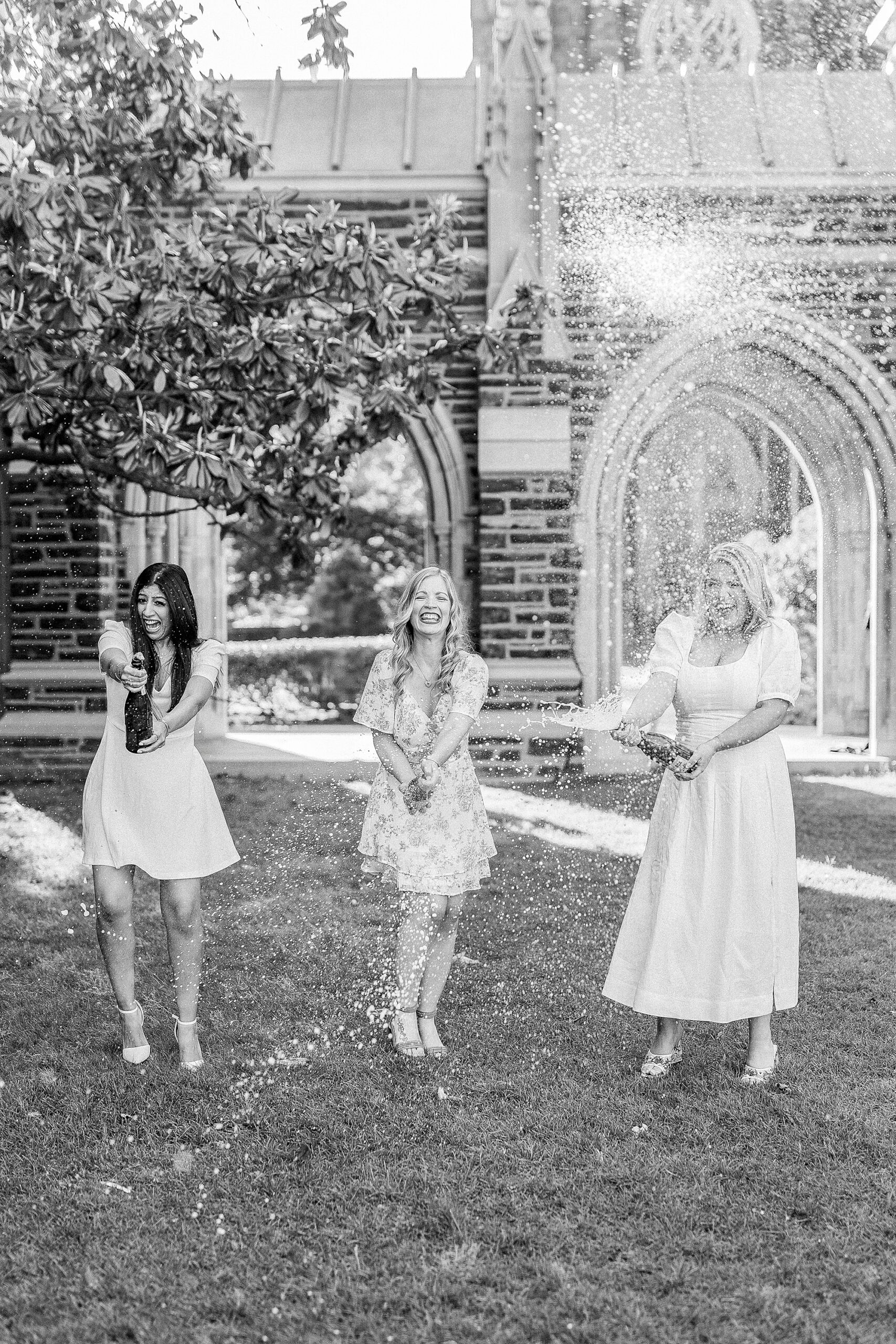 women pop champagne during graduation portraits at Duke University