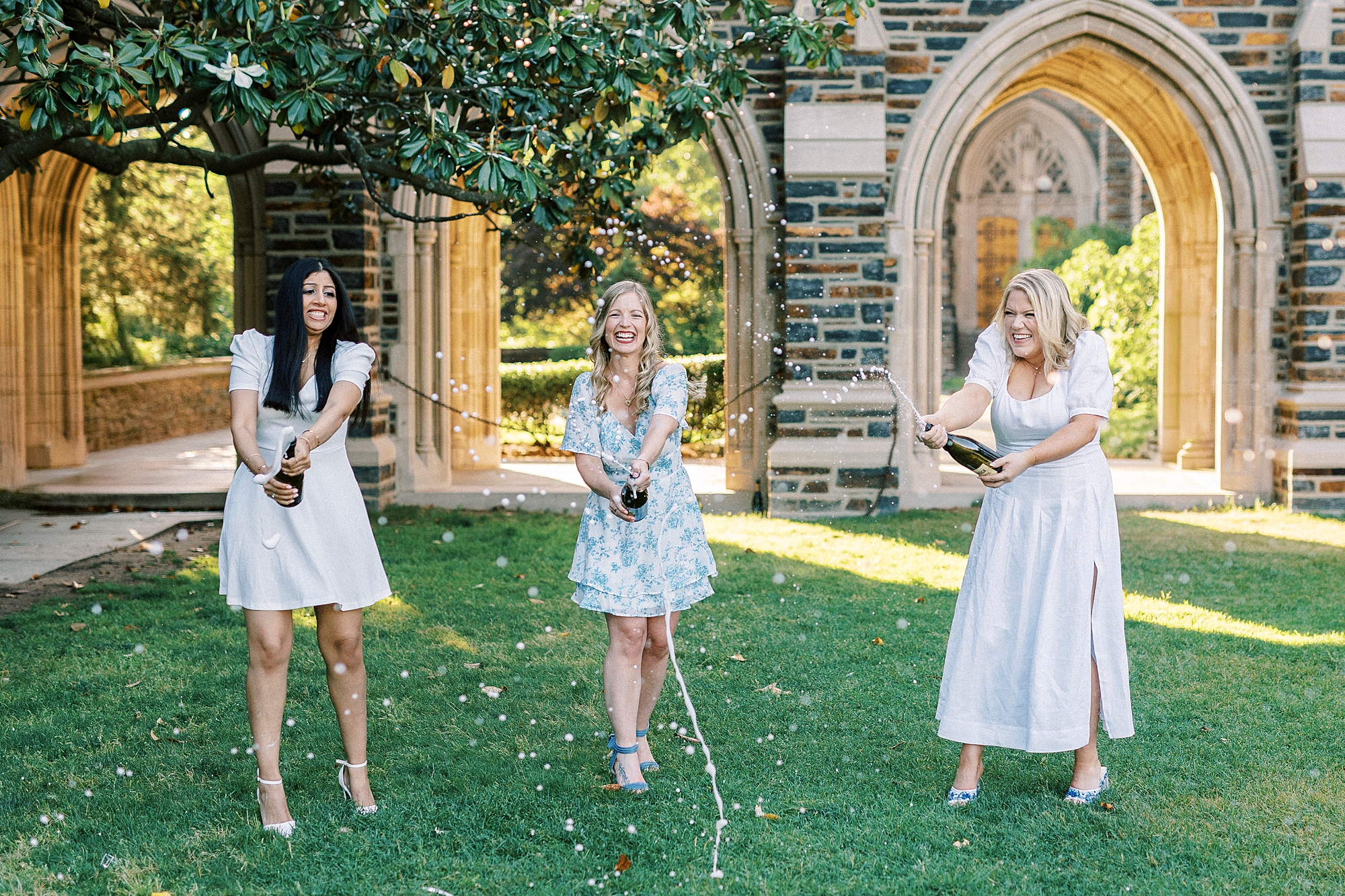 women pop Champagne during graduation portraits at Duke University