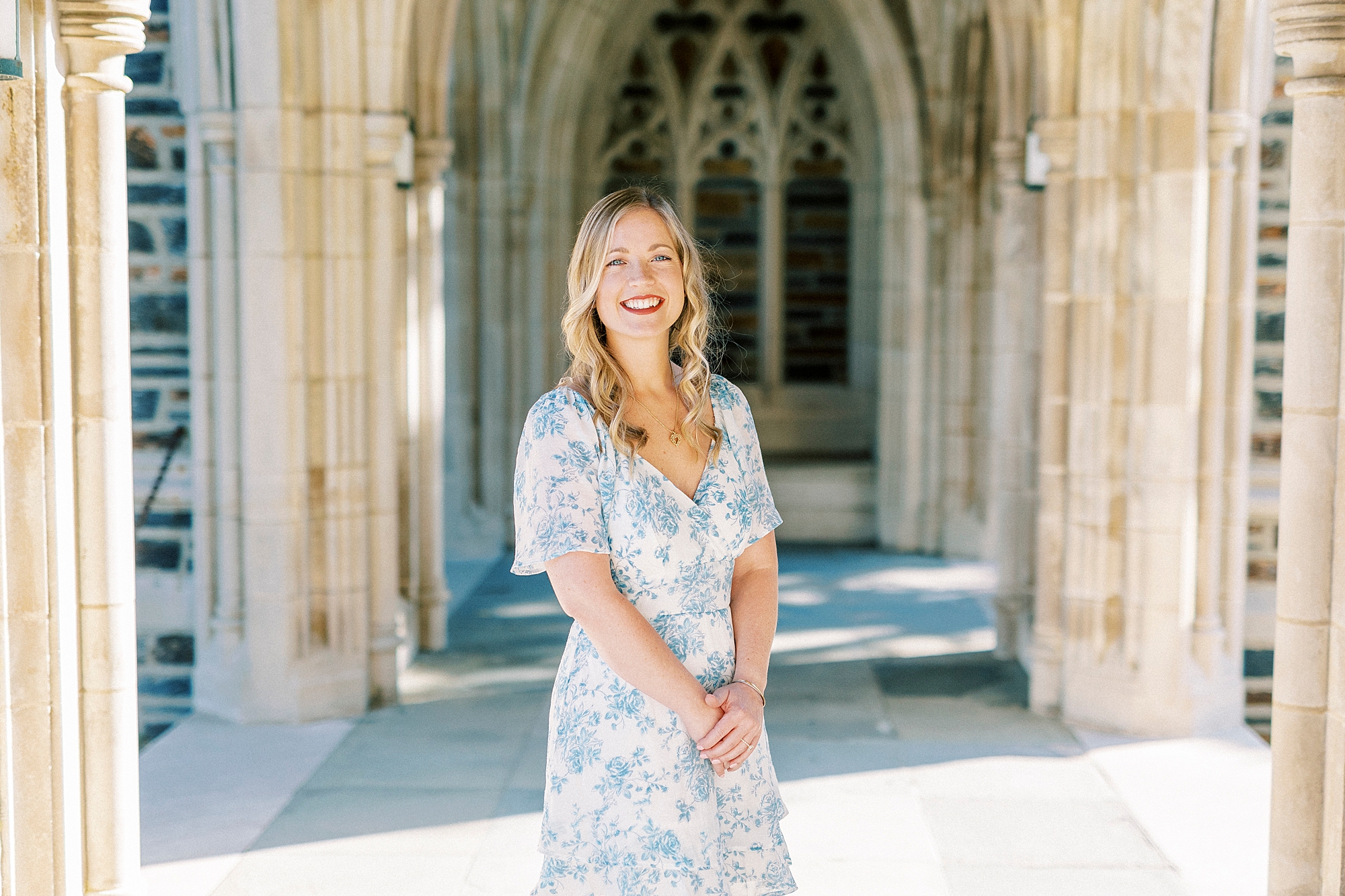 blonde woman in blue and white dress stands in archways of Duke Chapel 