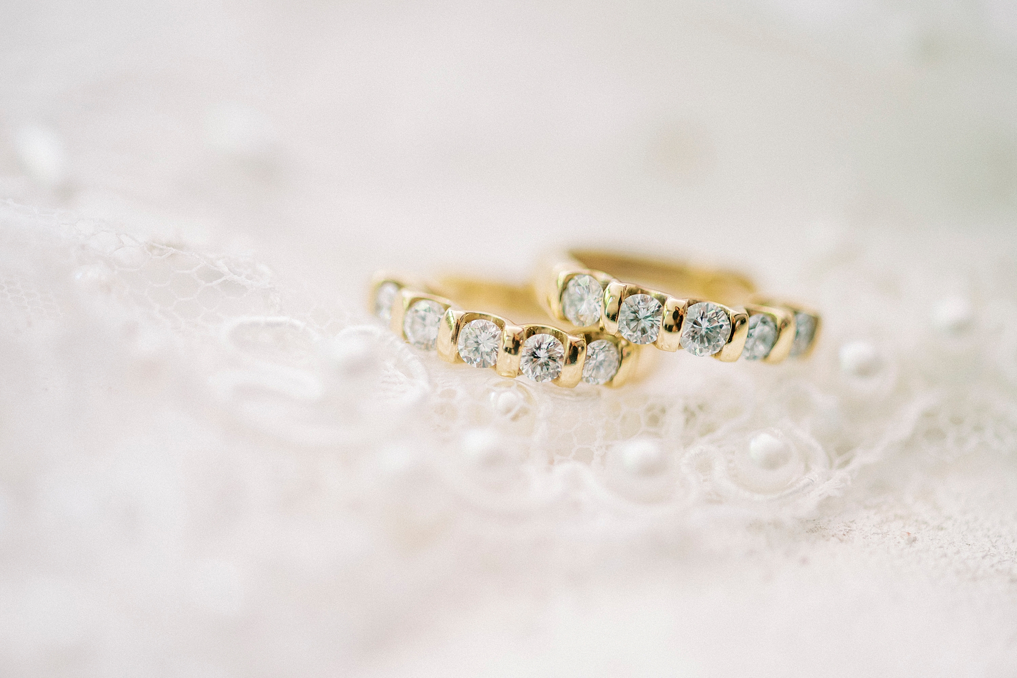 gold wedding band with diamonds lay on pearl veil