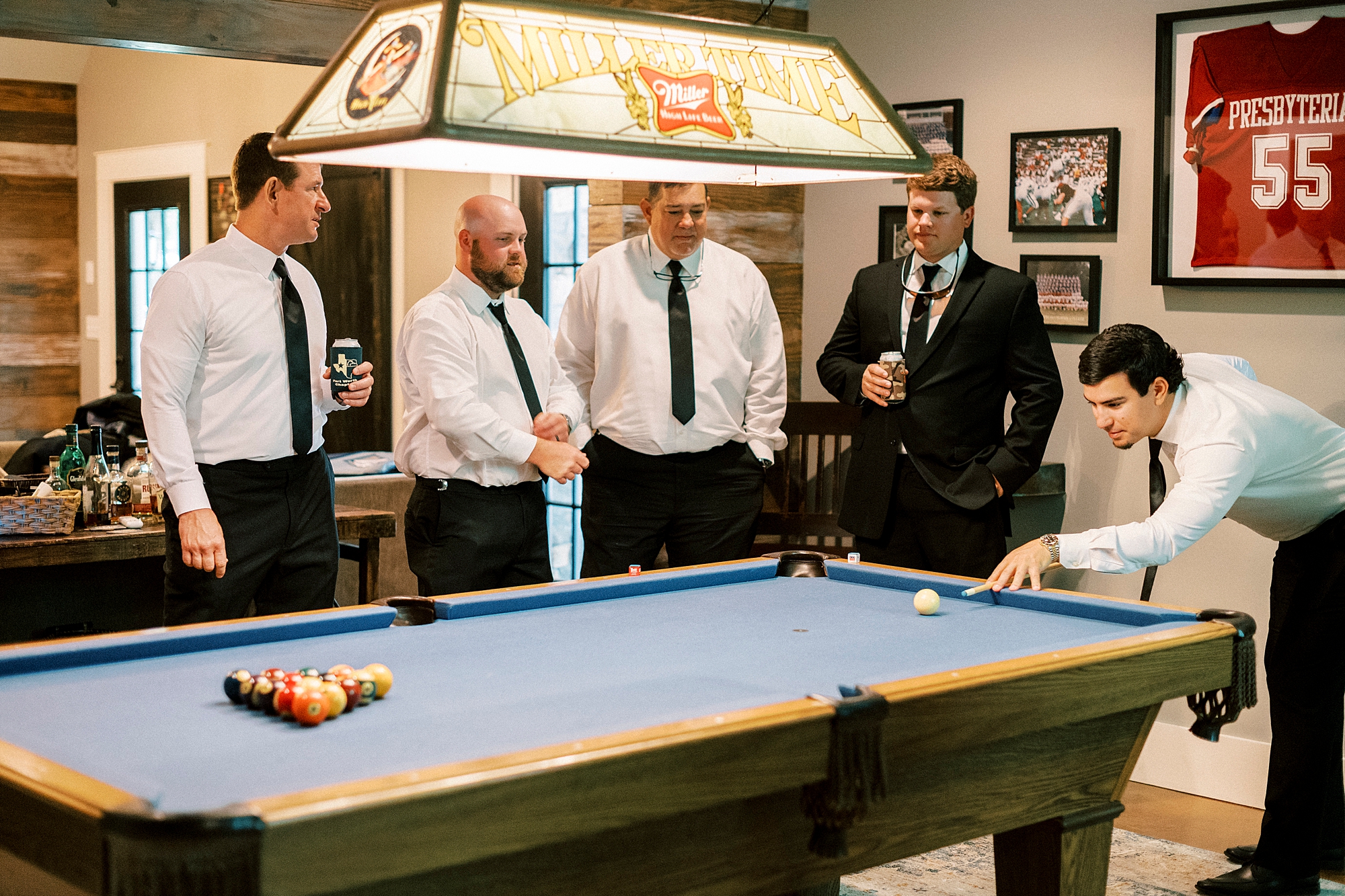 groomsmen stand around pool table preparing for wedding