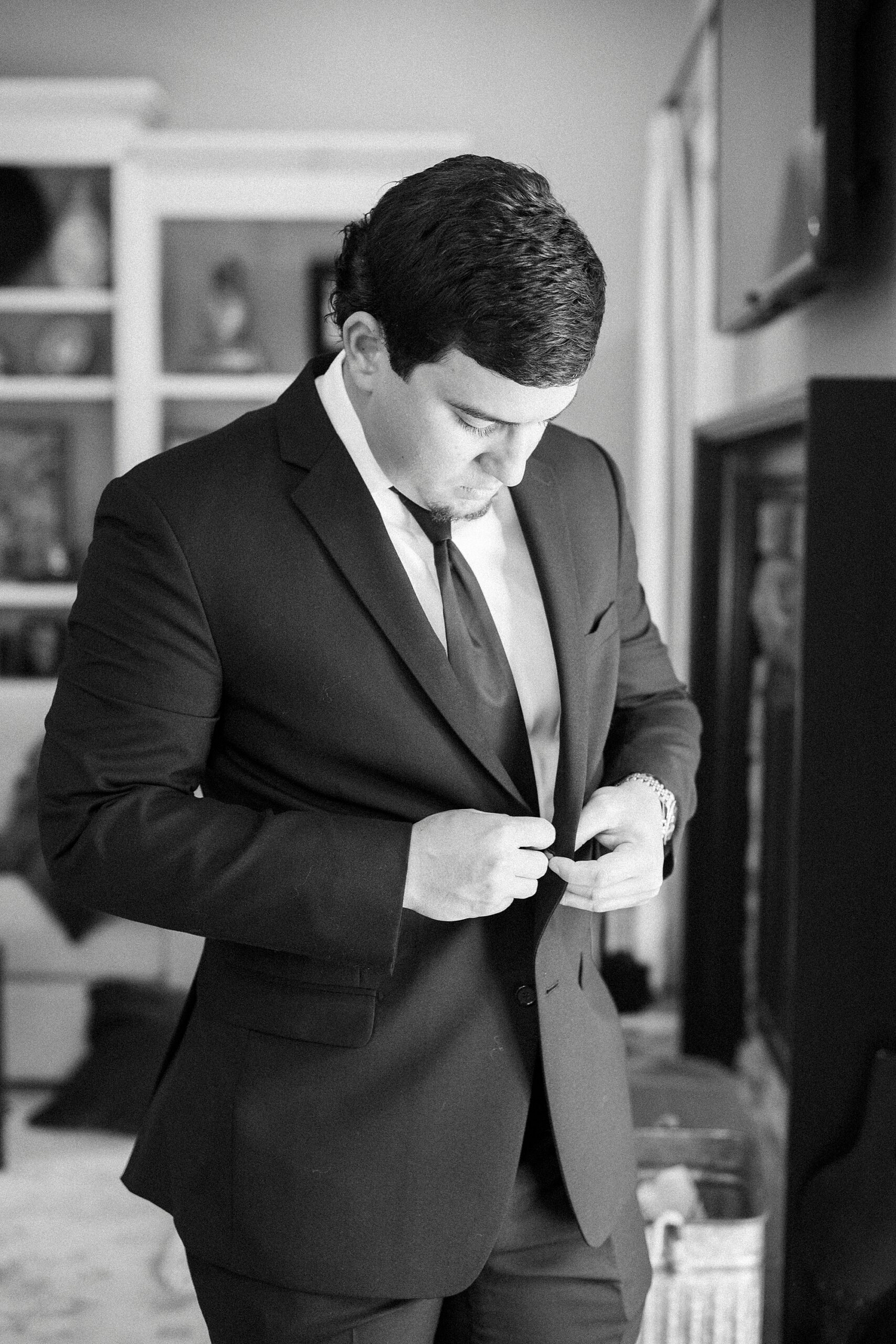 groom buttons up suit jacket during wedding prep in Unionville NC