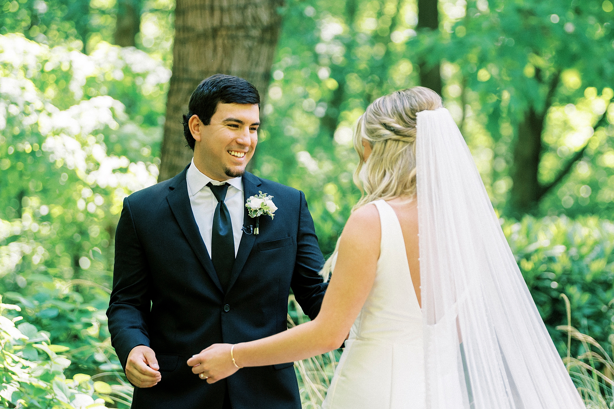 groom grins looking at bride during first look on wedding day