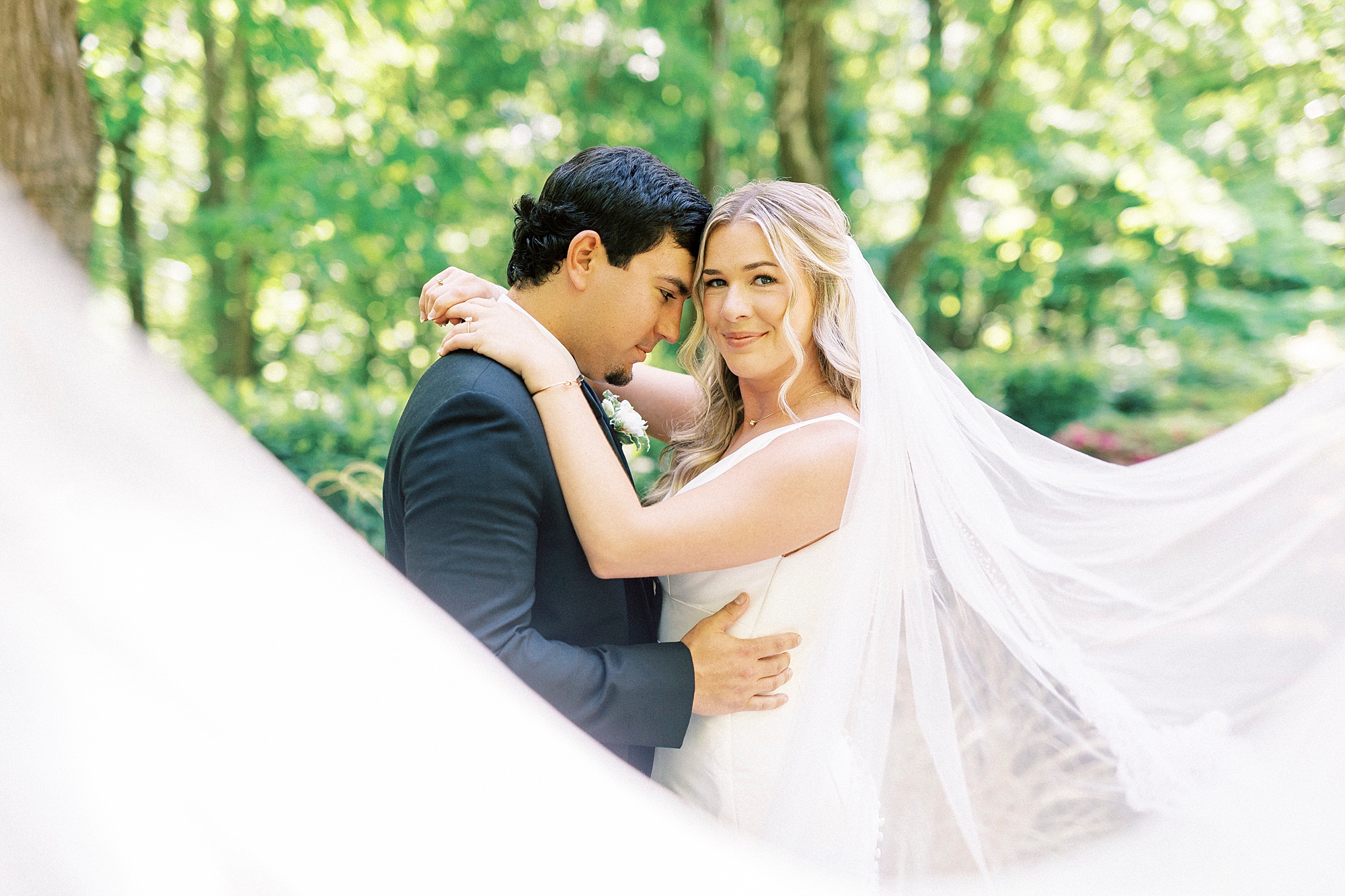 bride and groom lean heads together with veil pulled around them