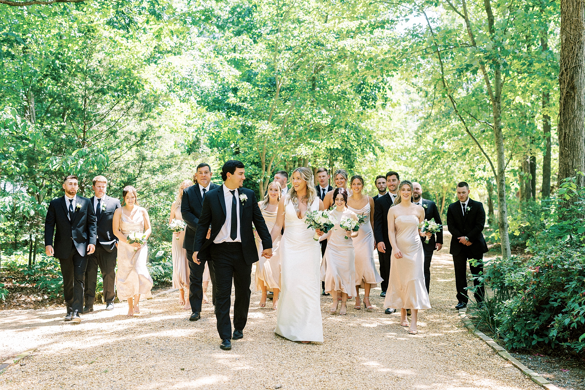 bride and groom hold hands walking with wedding party at Morning Glory Farm