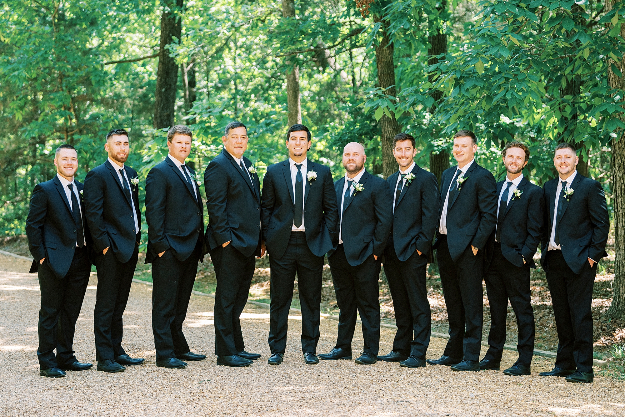 groom stands with groomsmen in black suits at Morning Glory Farm