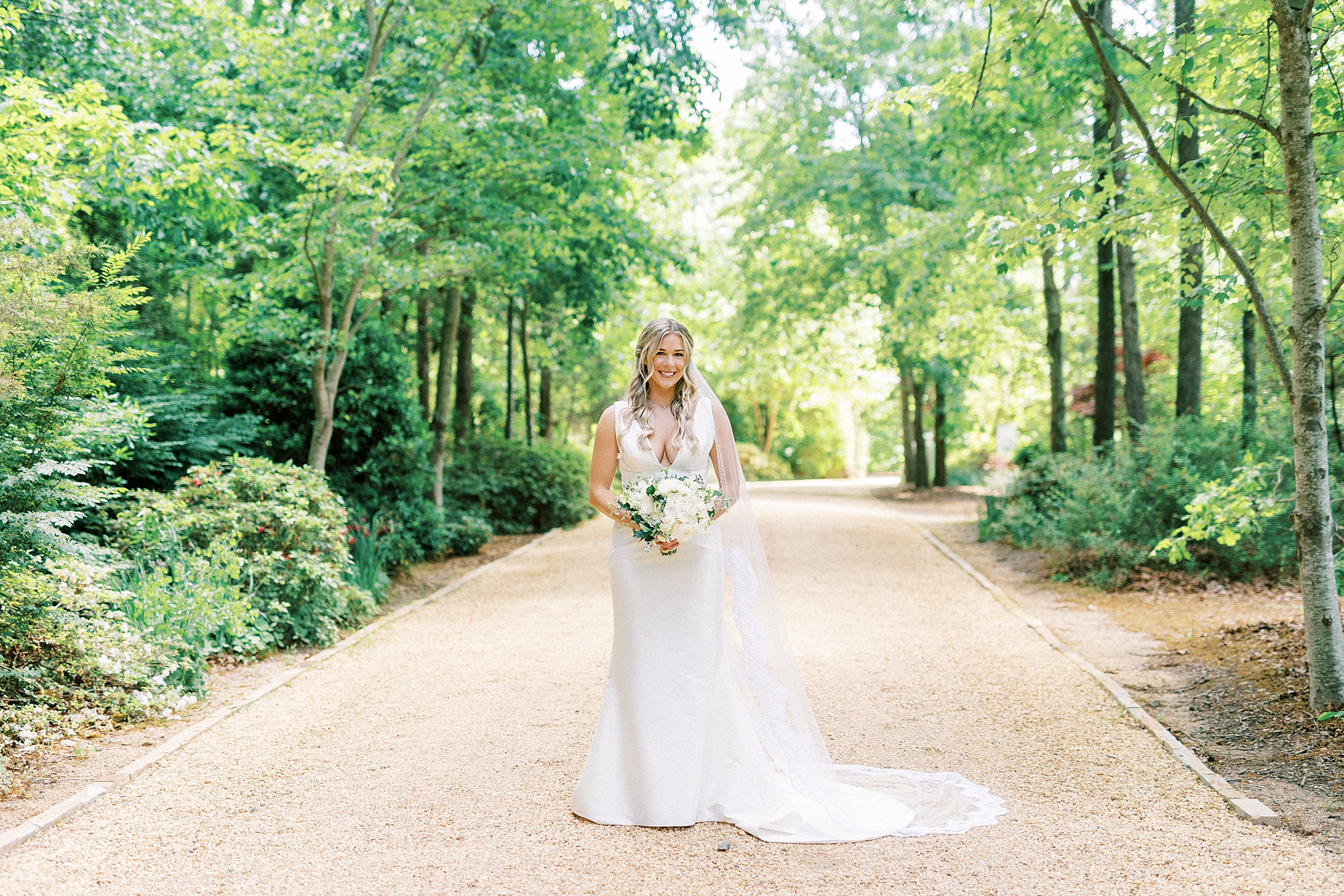 bride stands holding bouquet on driveway at Morning Glory Farm