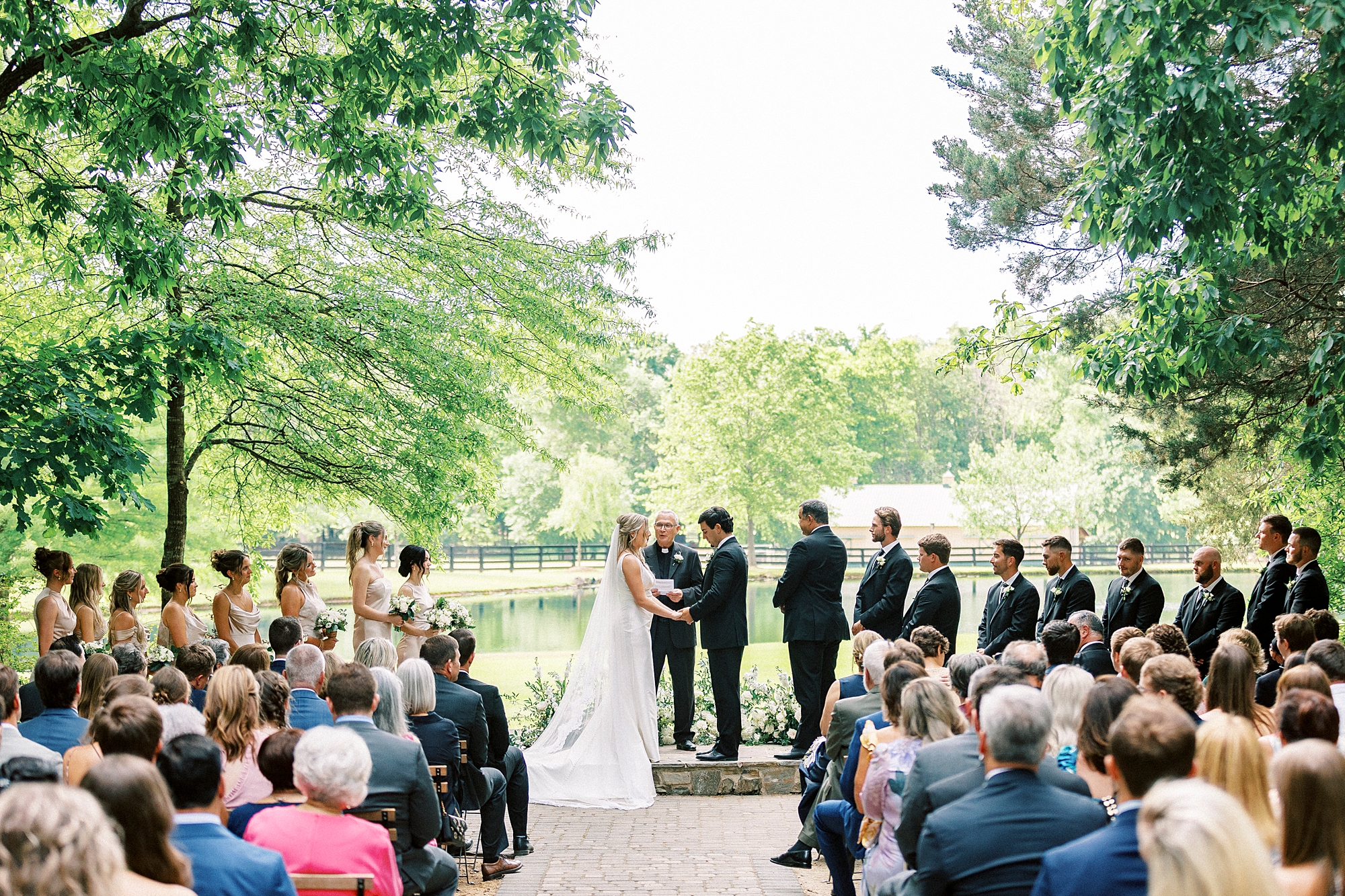 newlyweds stand together overlooking pond at Morning Glory Farm