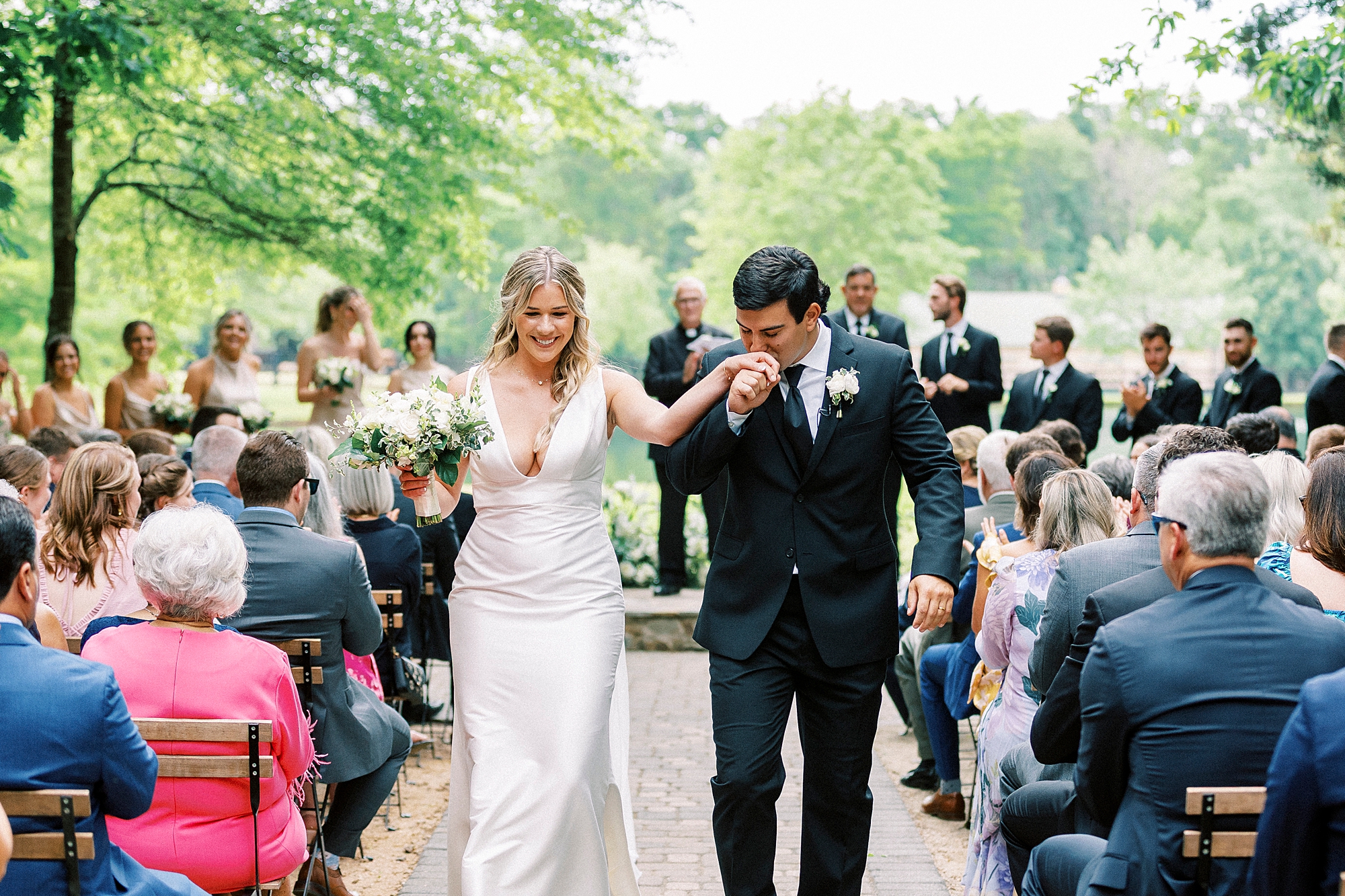 groom kisses bride's hand leaving wedding ceremony at Morning Glory Farm