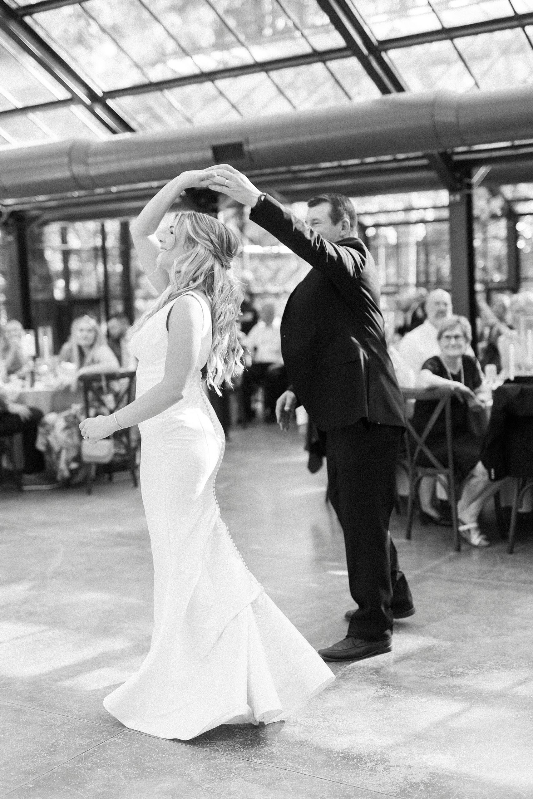 dad twirls bride on dance floor during NC wedding reception in glass house