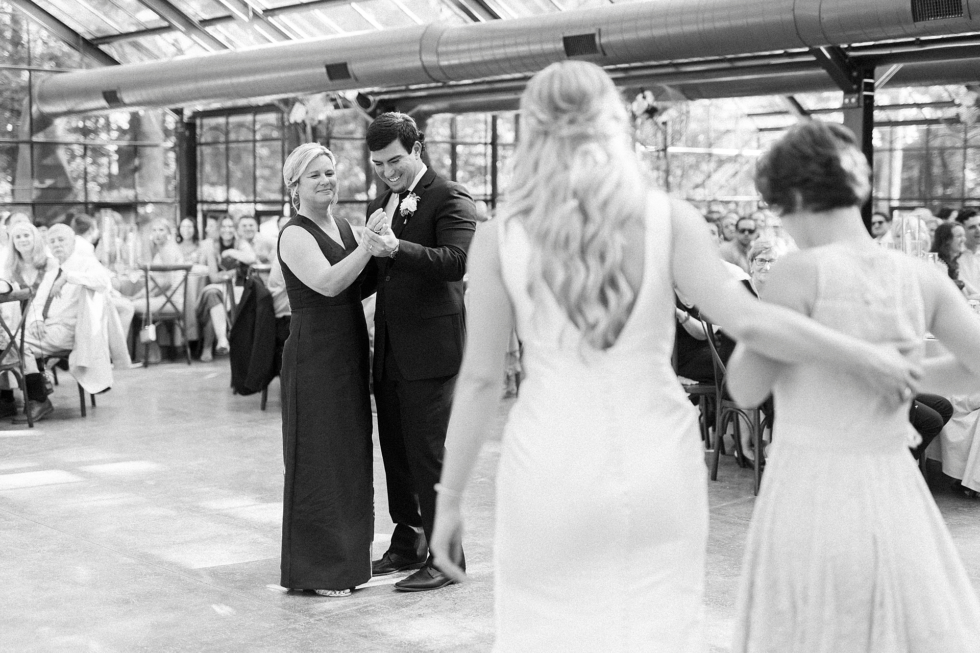bride and family watch groom dance with mother at Morning Glory Farm