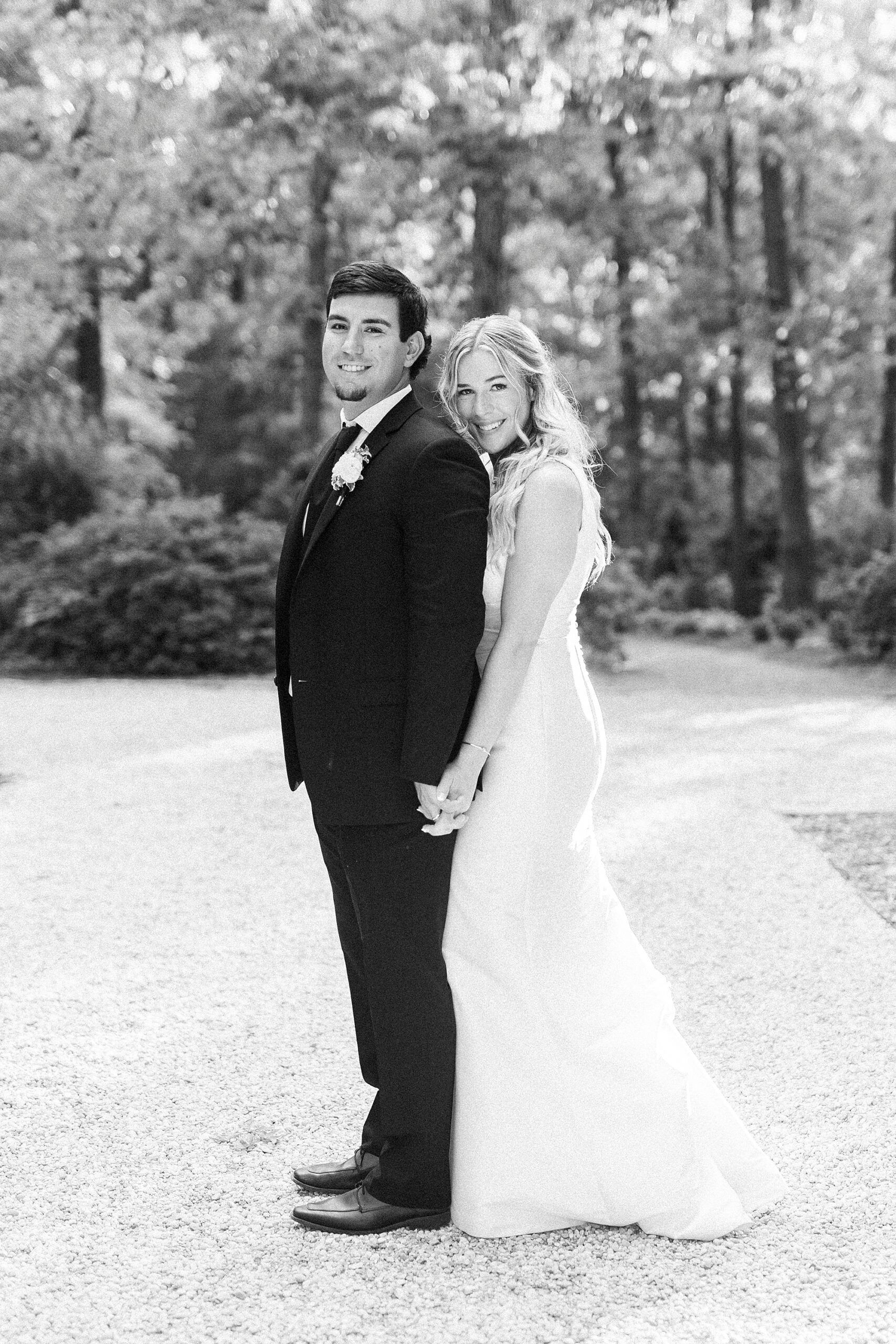 bride hugs groom from behind standing on driveway at Morning Glory Farm