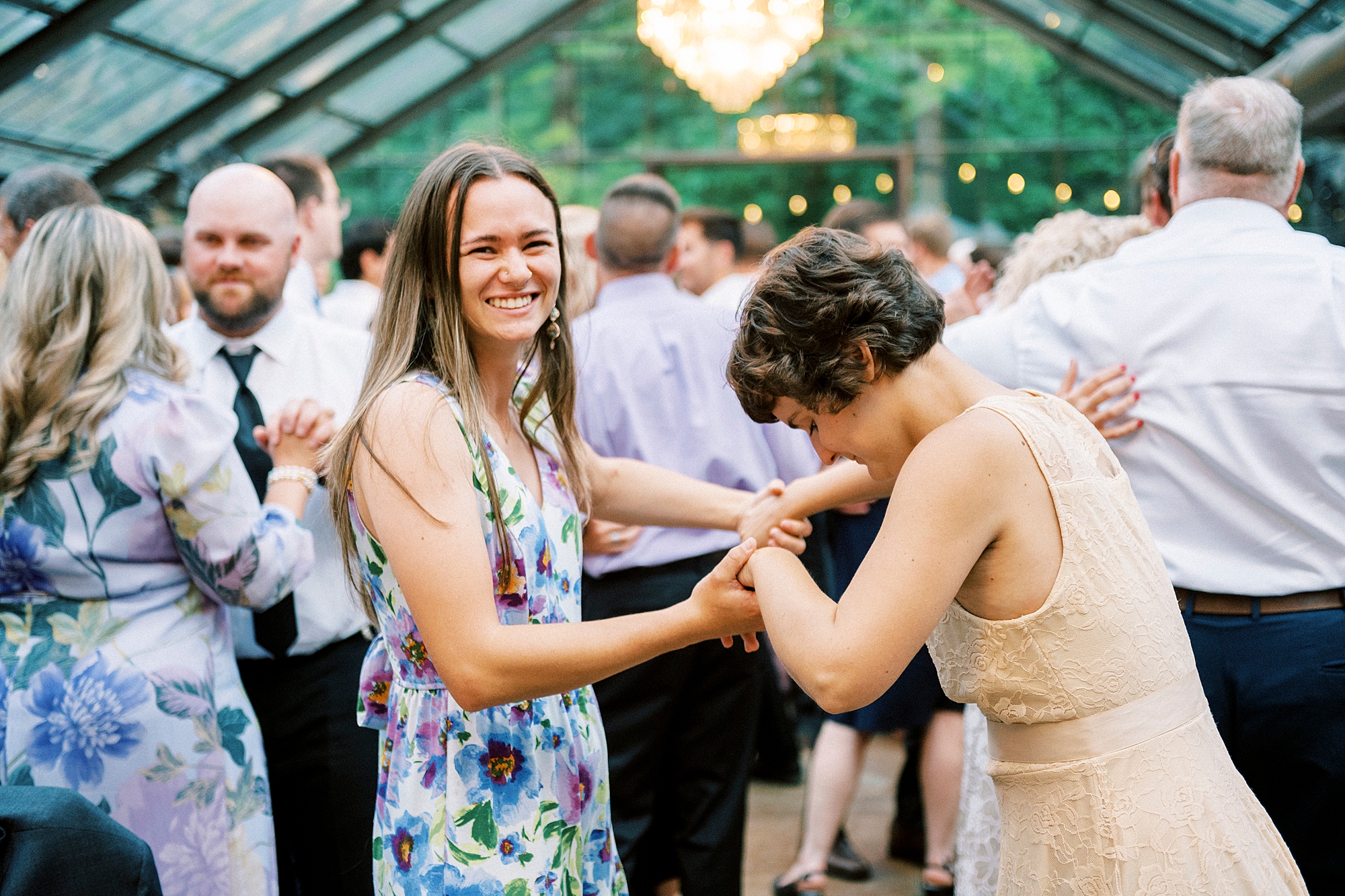 woman dances with wedding guest in glass house at Morning Glory Farm
