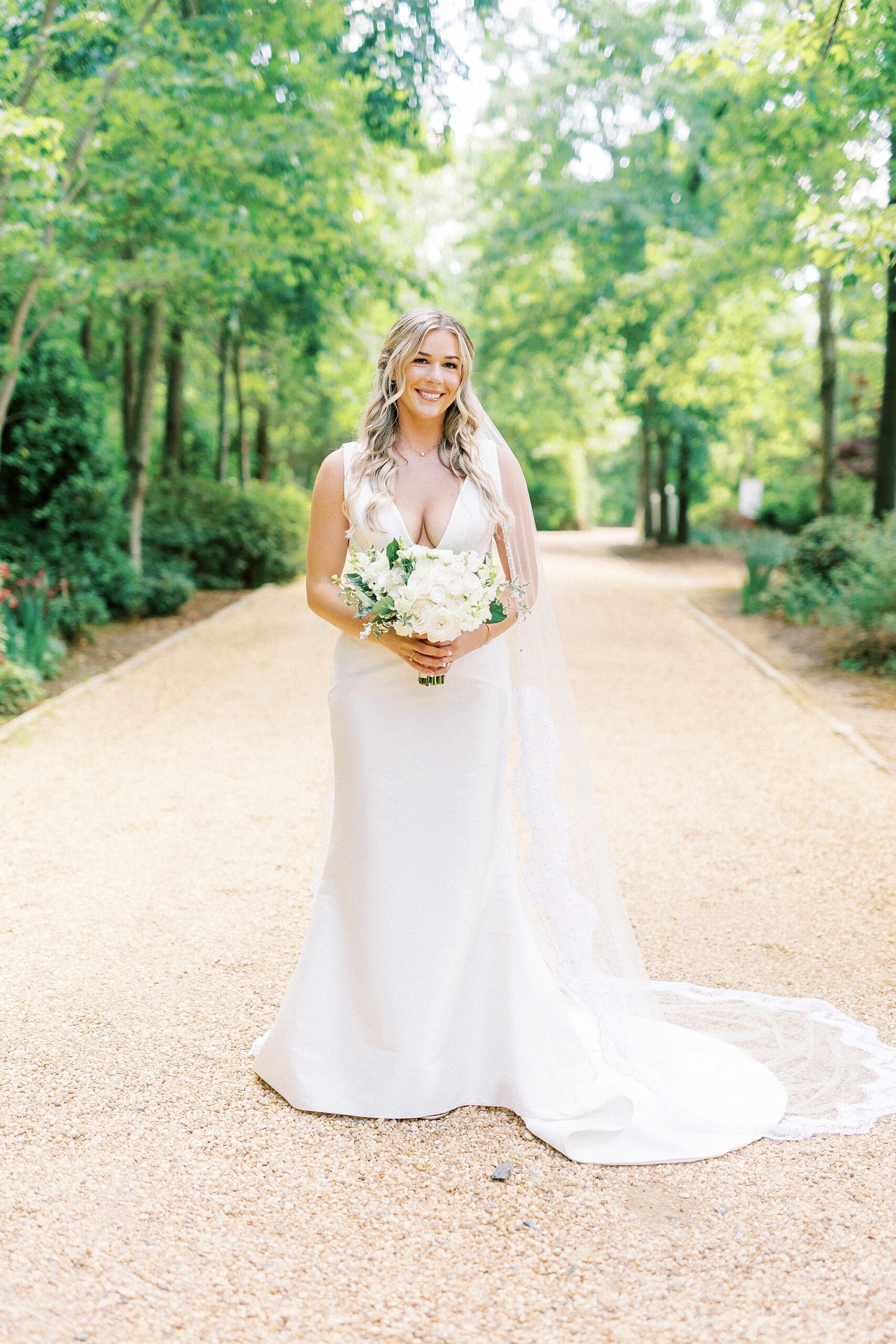 bride stands holding bouquet of all white flowers