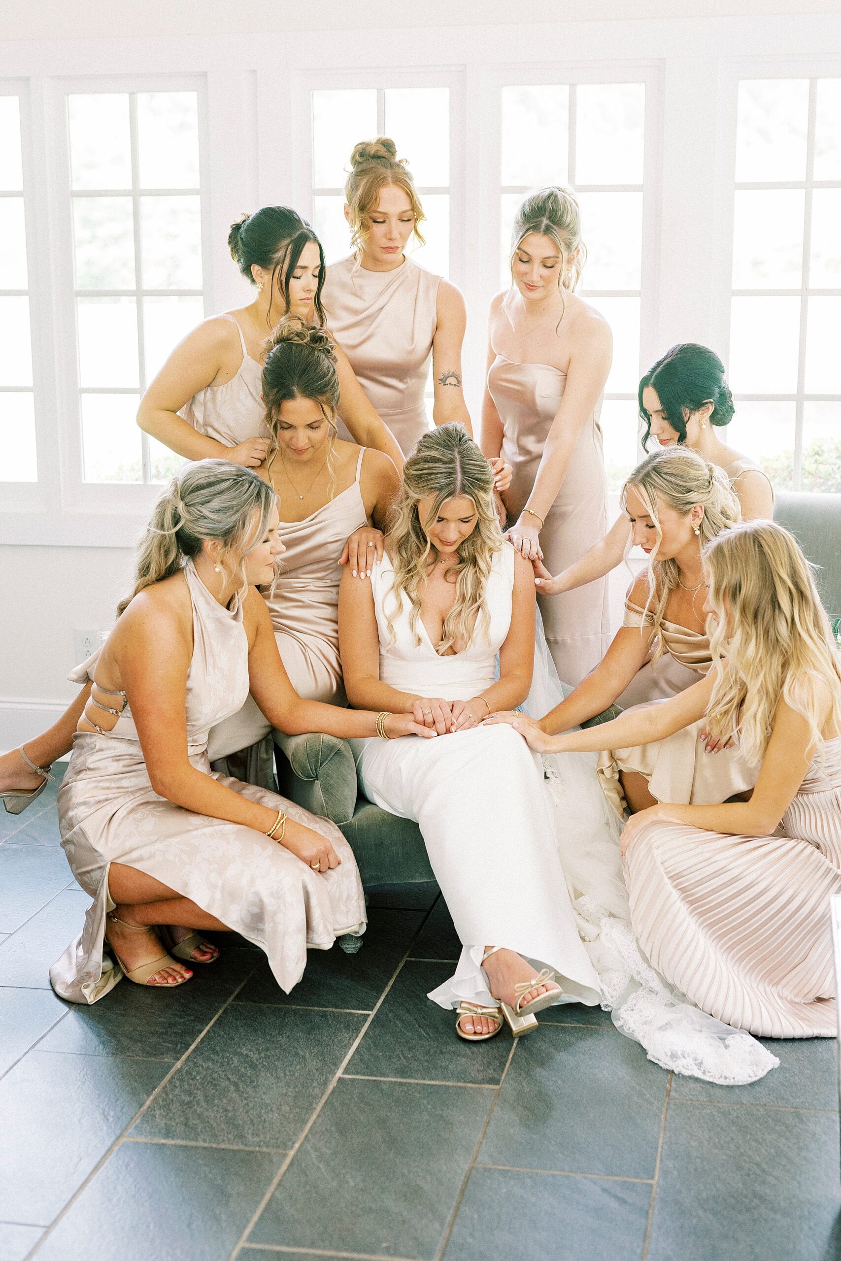 bridesmaids in champagne gowns pray over bride in suite at Morning Glory Farm