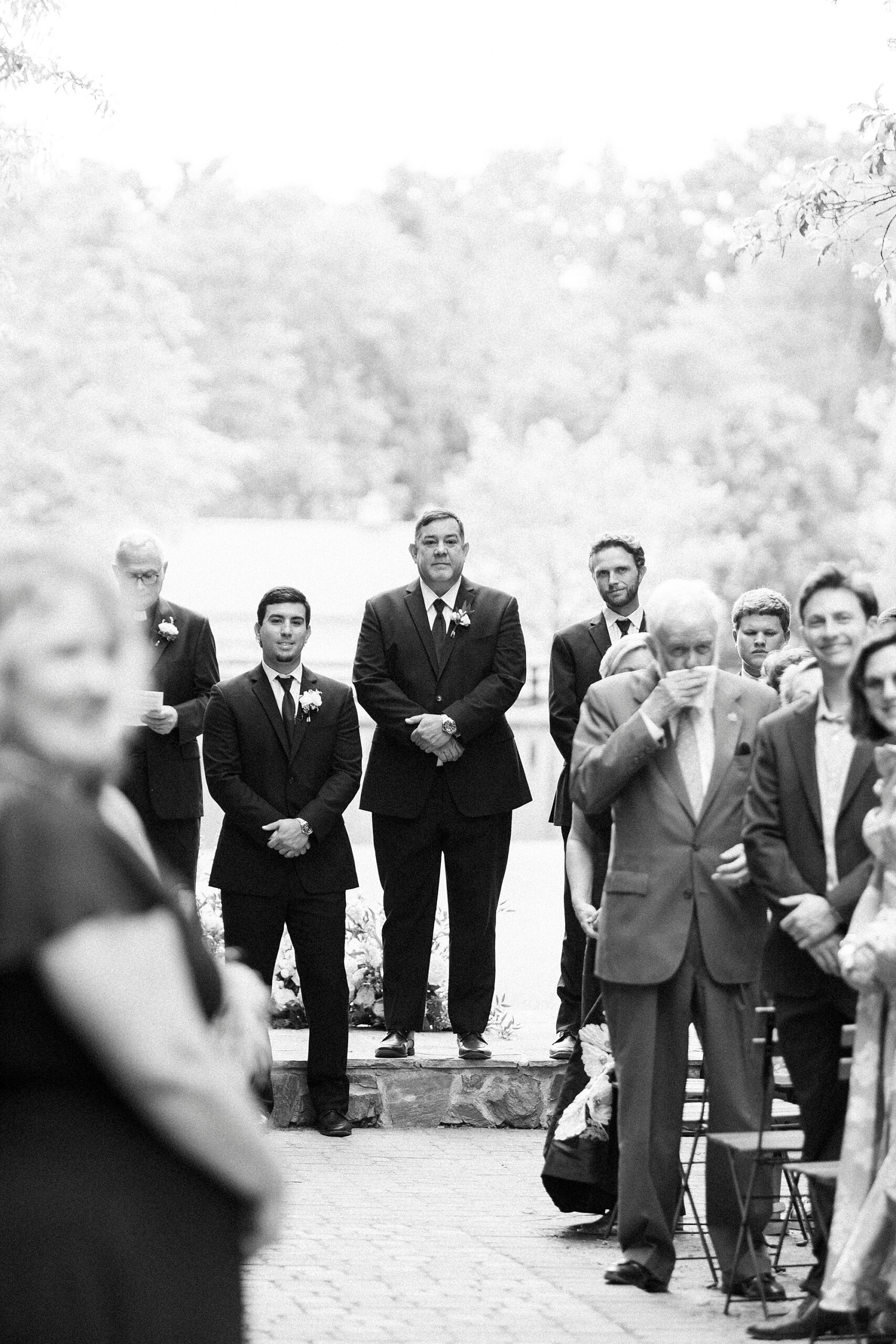 groom and officiant wait at end of the aisle at Morning Glory Farm