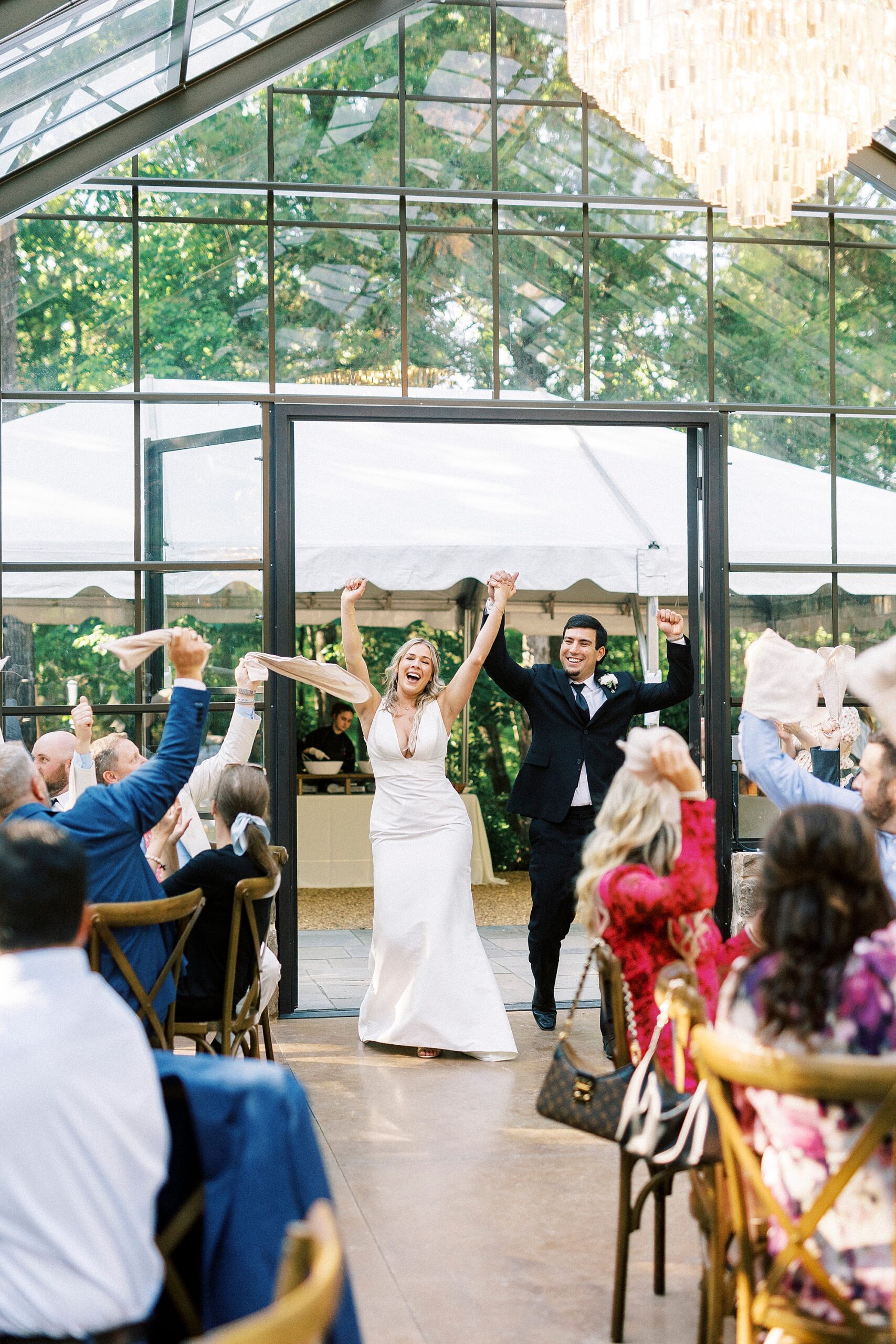 newlyweds cheer entering wedding reception in glass house at Morning Glory Farm