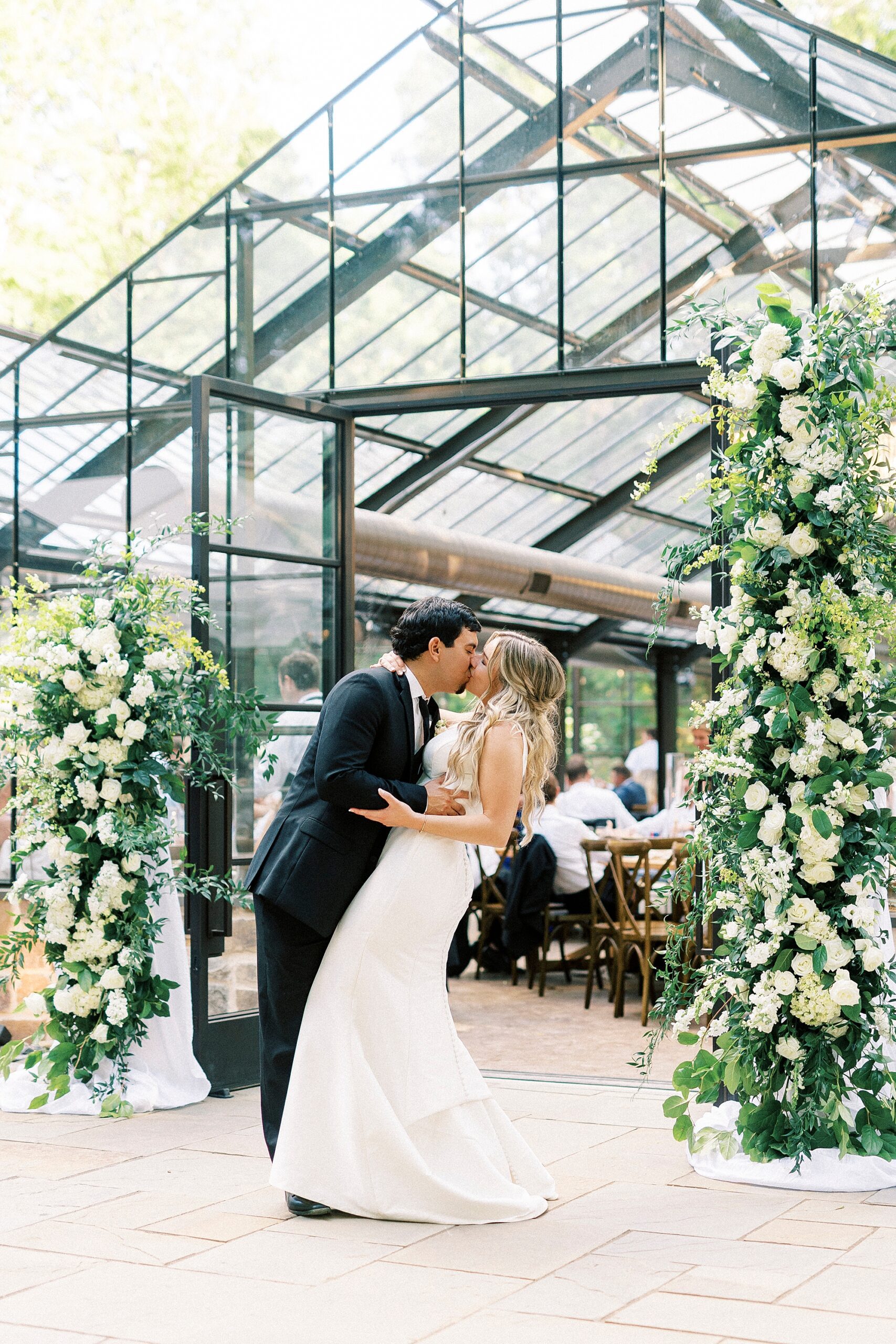 bride and groom kiss outside glass house at Morning Glory Farm