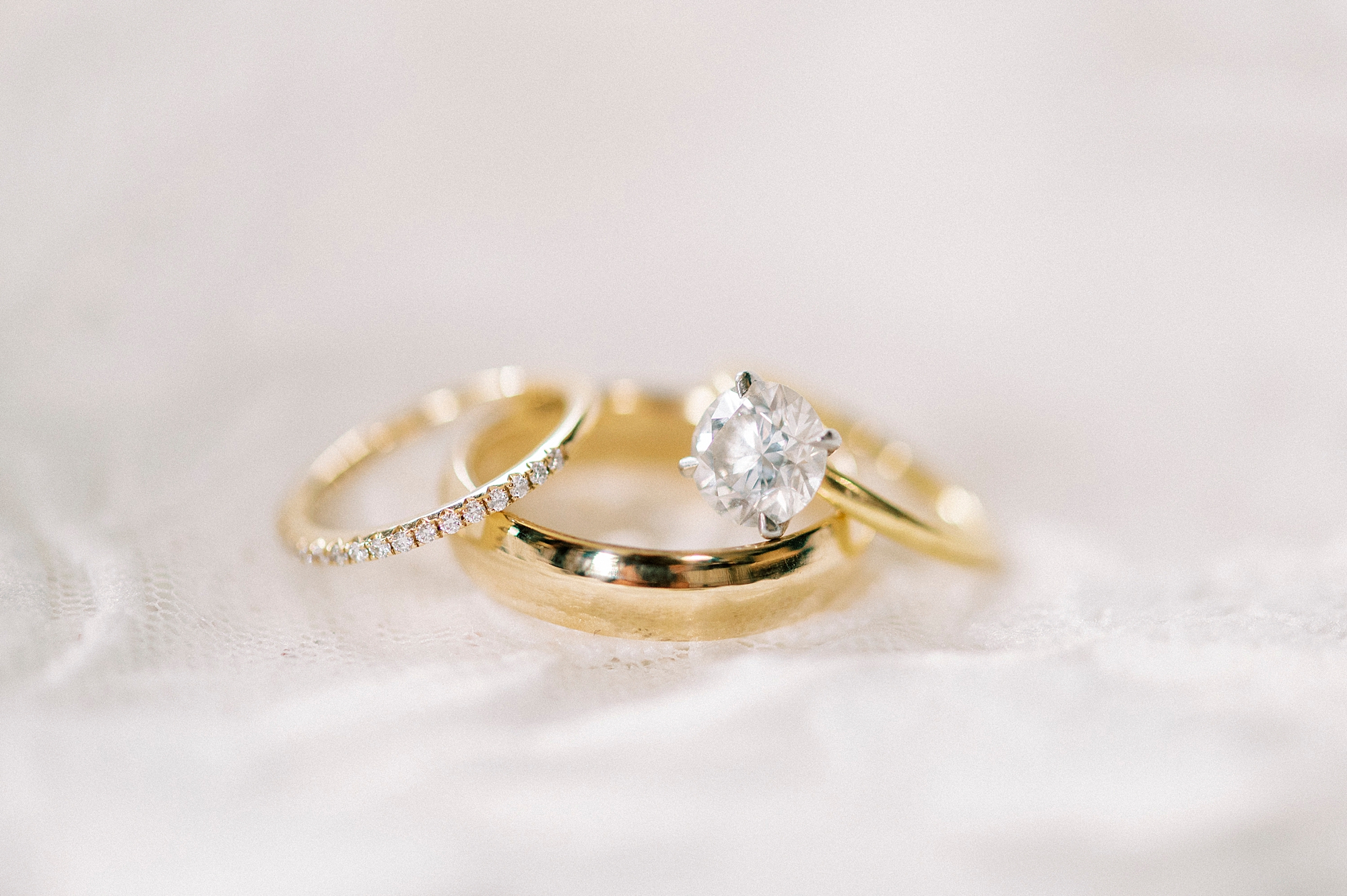 three gold wedding rings lay together on white veil