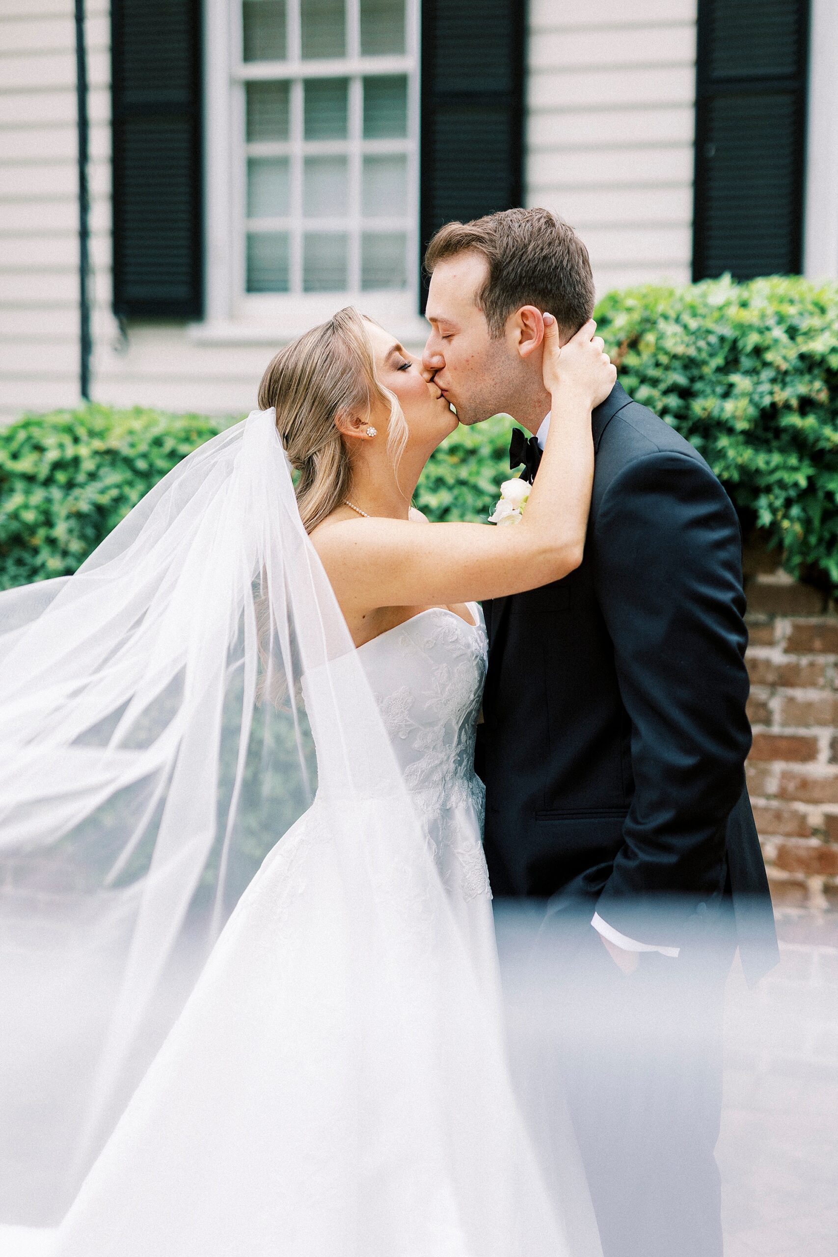 bride and groom kiss with veil pulled around them 