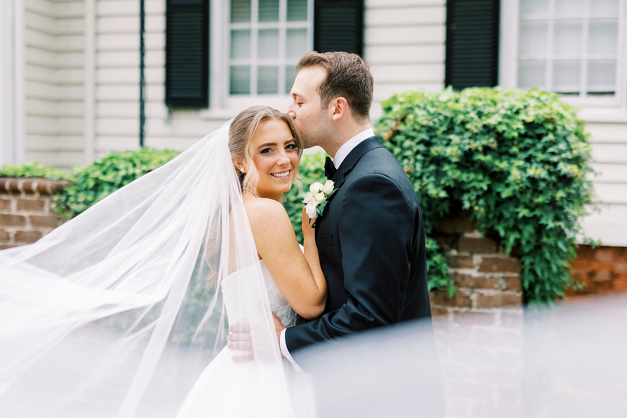groom kisses bride's head in front of the Sutherland