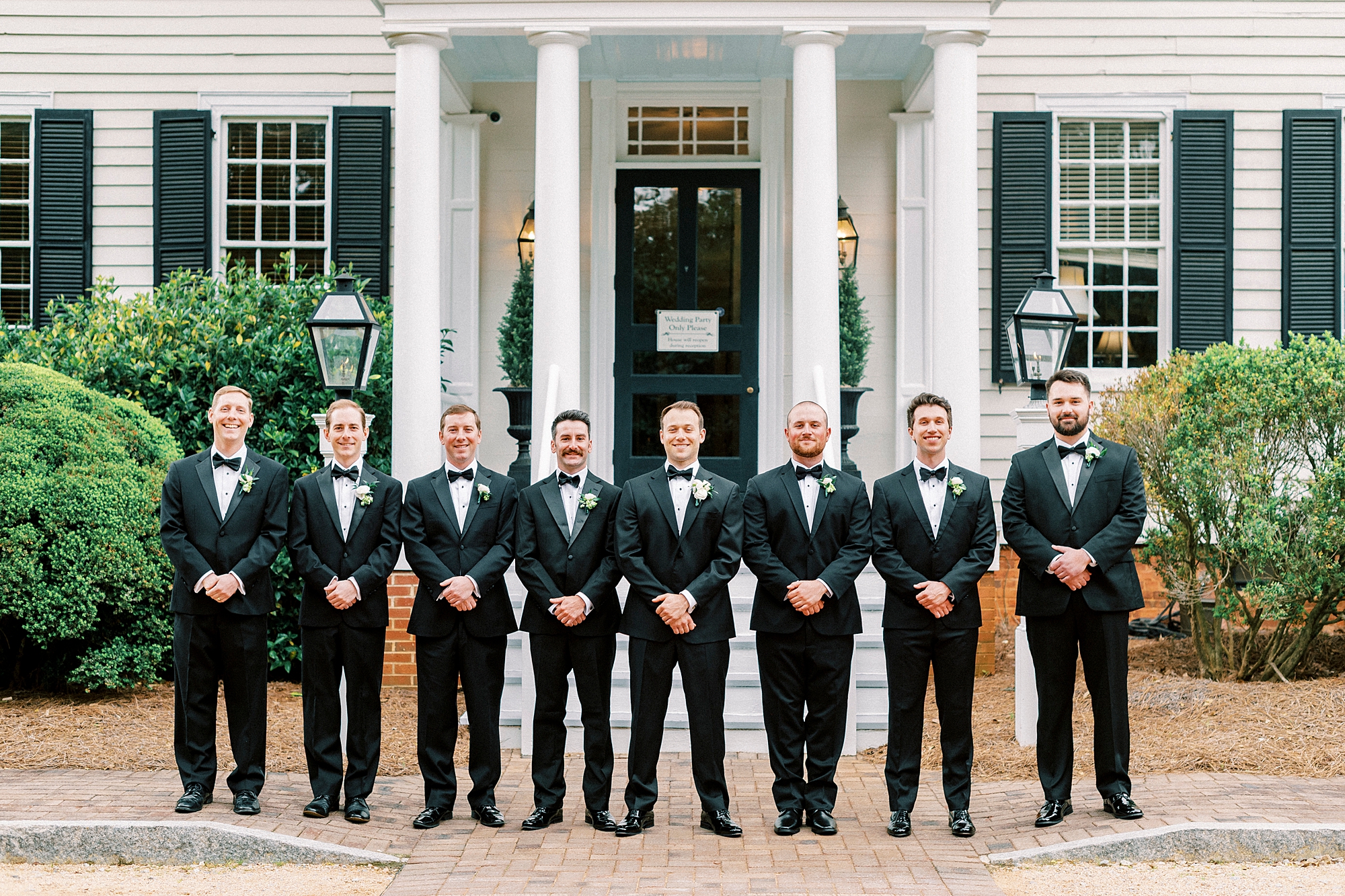 grooms stands in line with groomsmen in front of the Sutherland