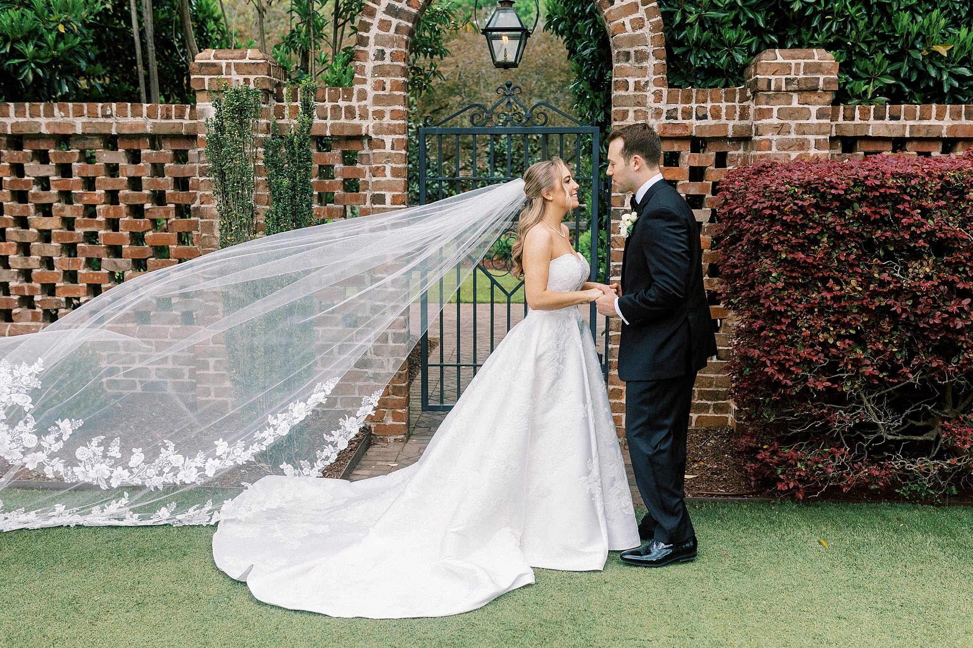 bride and groom smile in front of brick archway at the Sutherland
