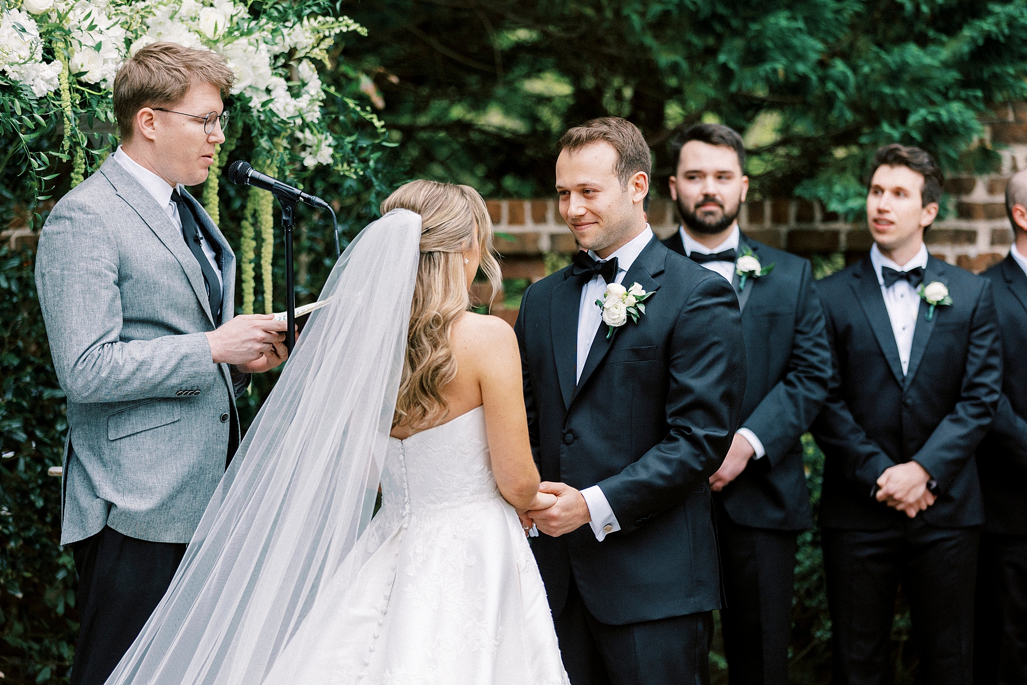 bride and groom hold hands during wedding ceremony in gardens of the Sutherland
