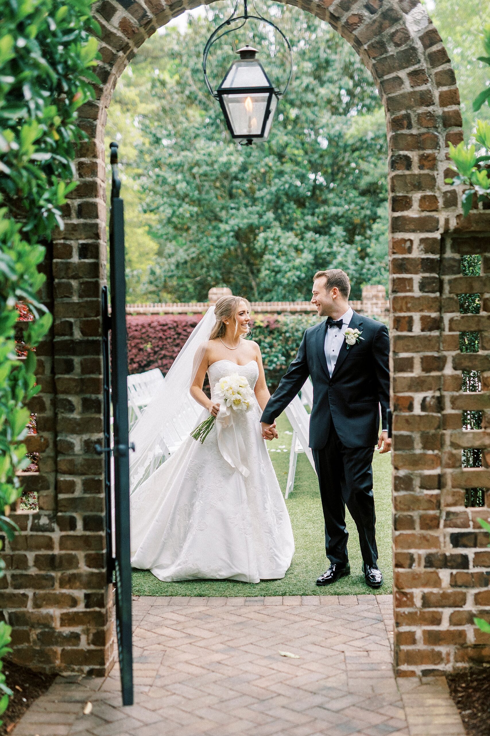 bride and groom walk through brick gateway at the Sutherland