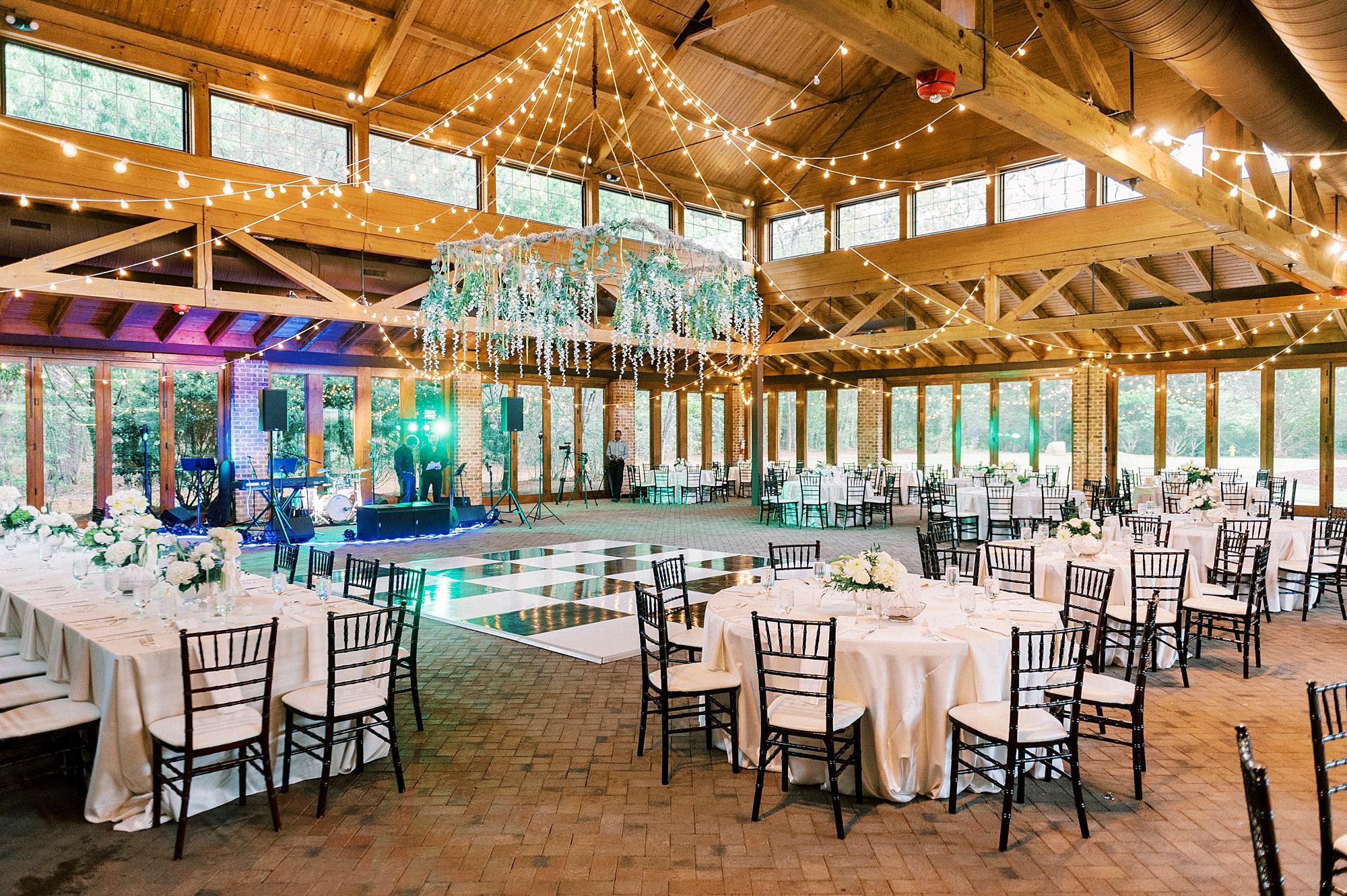 rustic wedding reception with greenery hanging from ceiling and black and white floor