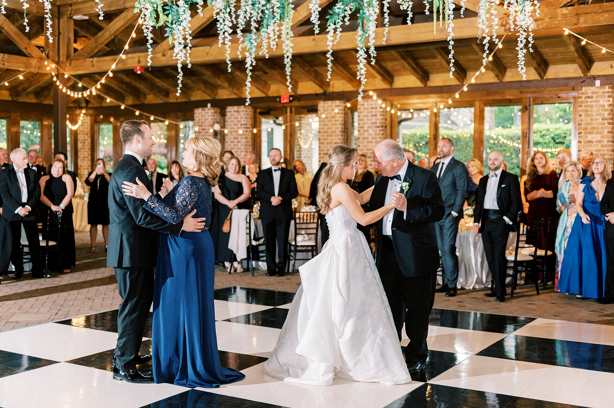 bride dances with father and groom dances with mother on black and white floor at the Sutherland Pavilion 