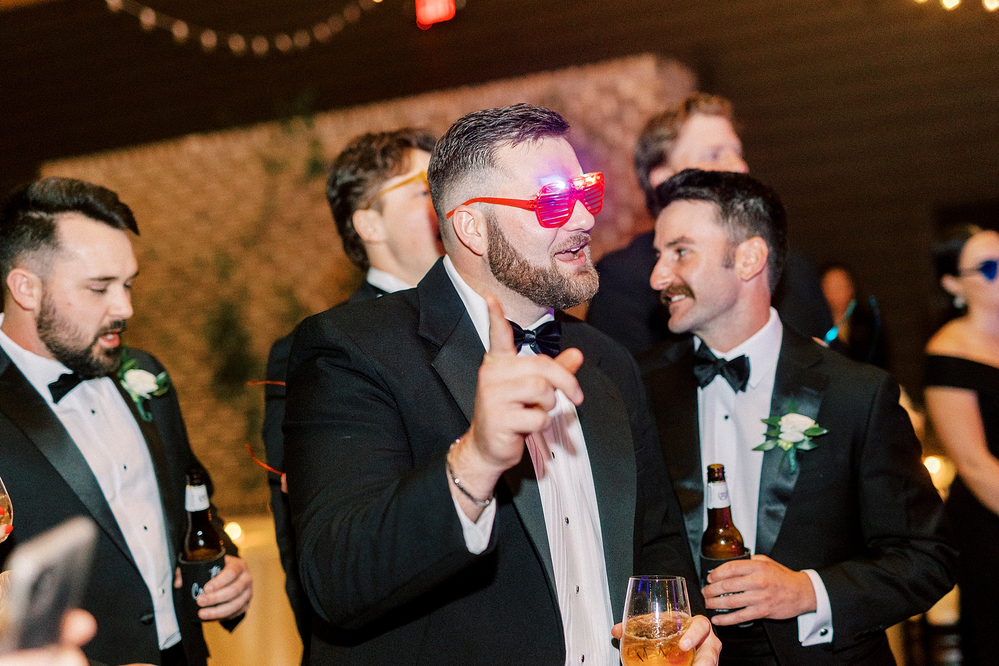 guest dances in neon sunglasses during Wake Forest NC wedding reception in pavilion