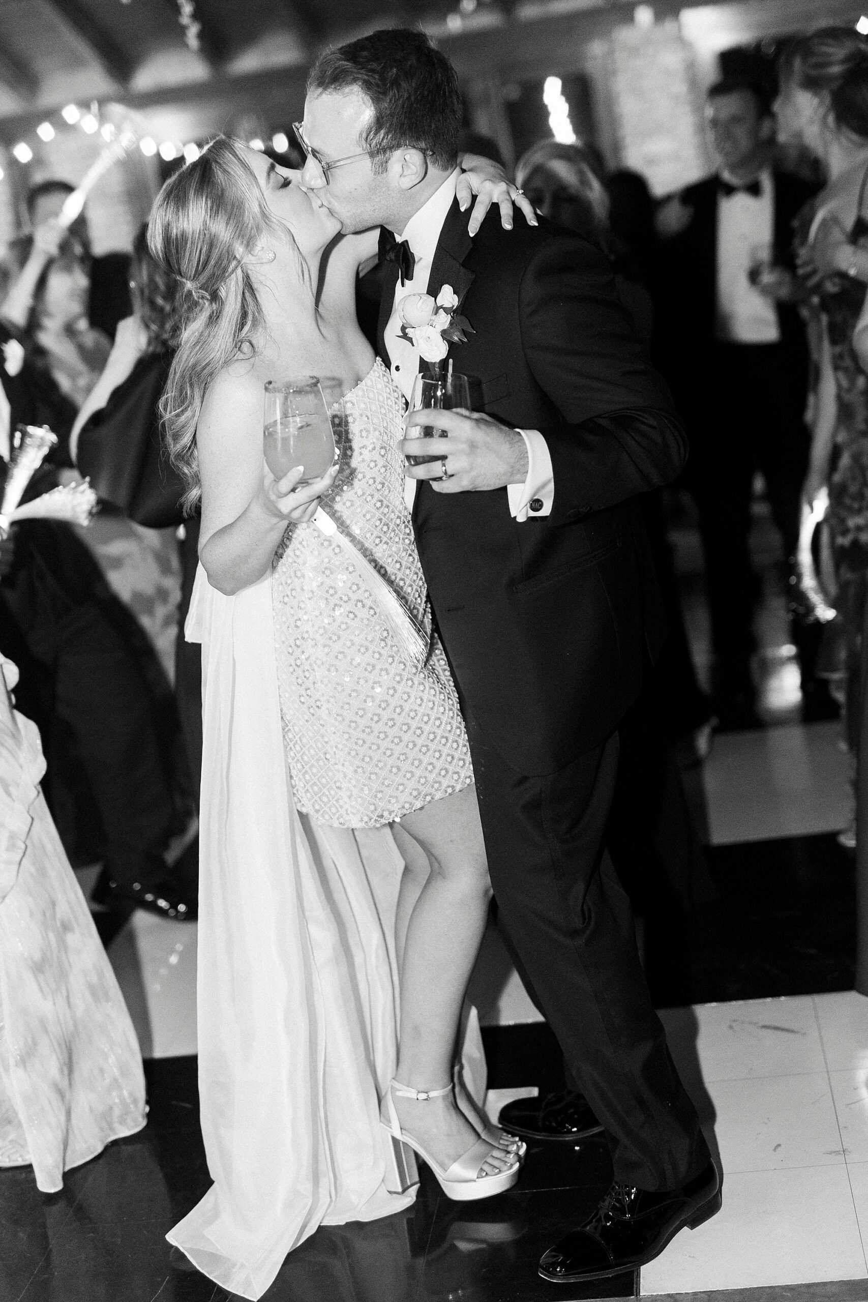 bride and groom kiss holding drinks during Wake Forest NC wedding reception in pavilion