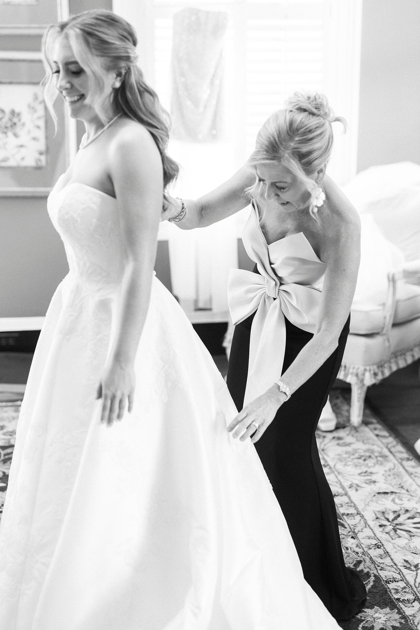 mother helps bride into wedding dress during prep in bridal suite 