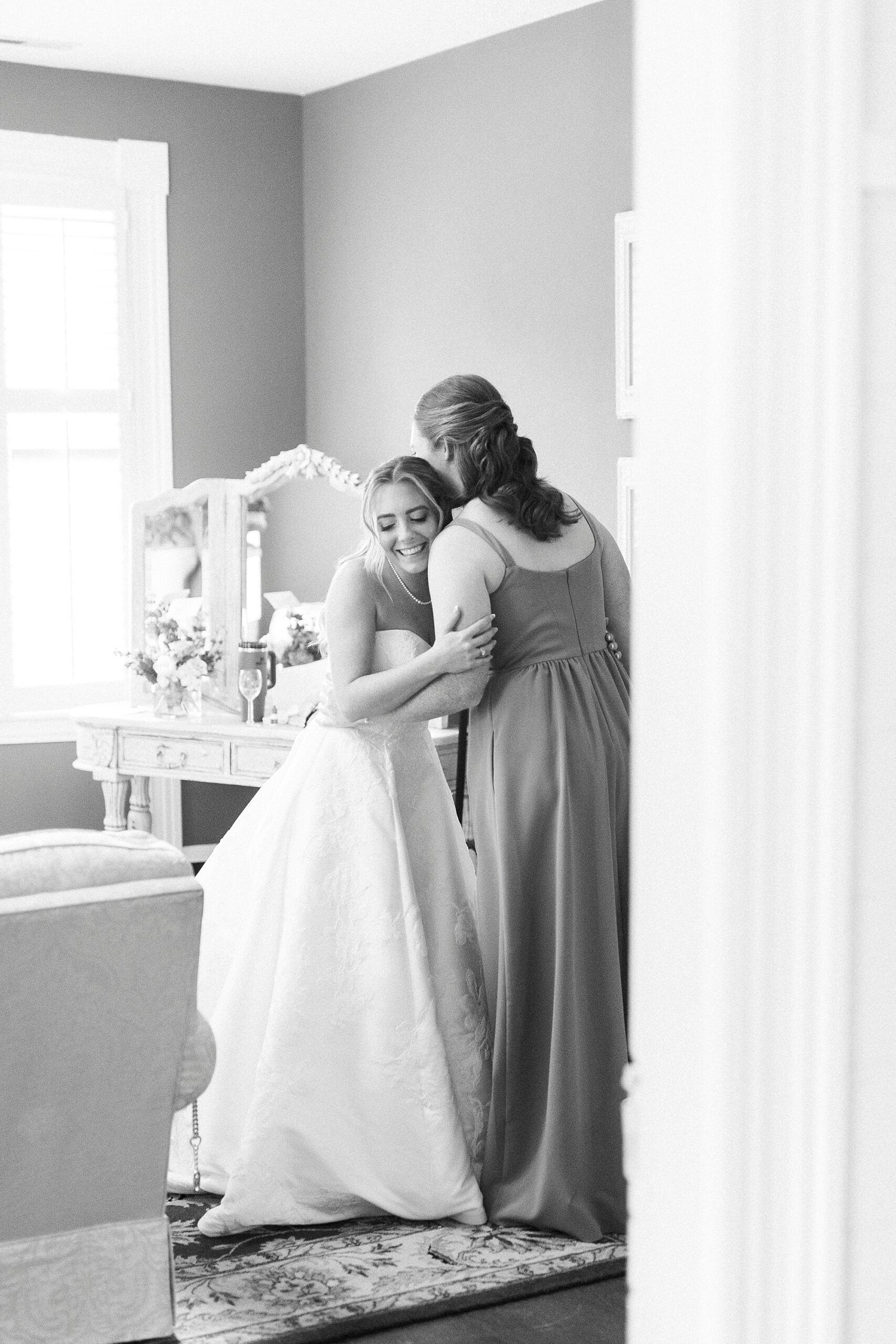 bride hugs bridesmaid during prep for NC wedding day