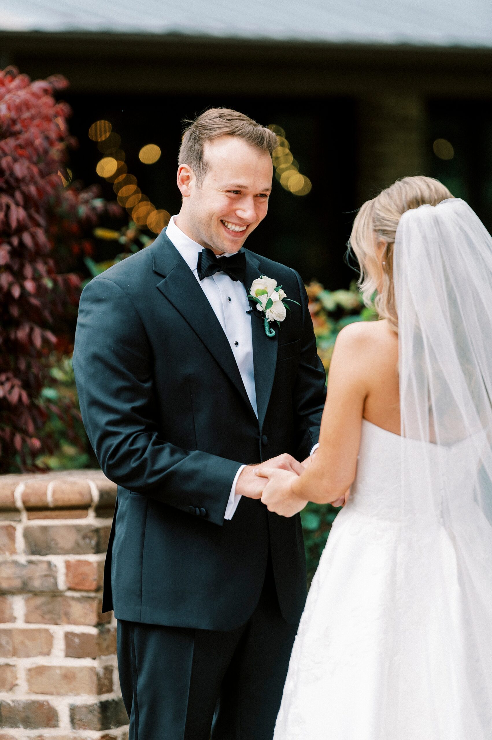 groom grins at bride during first look in Wake Forest NC