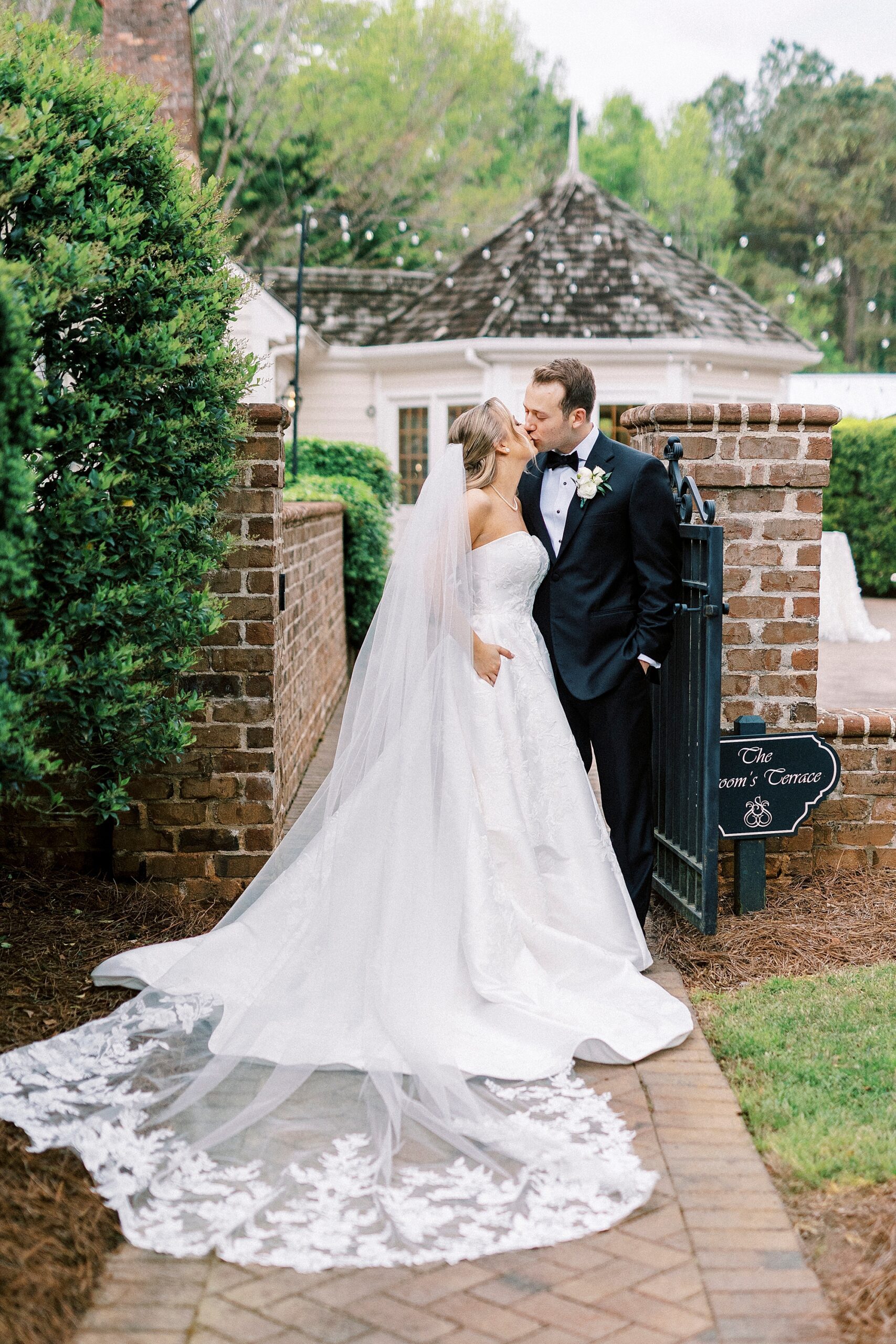 bride and groom stand in garden by brick archway t the Sutherland