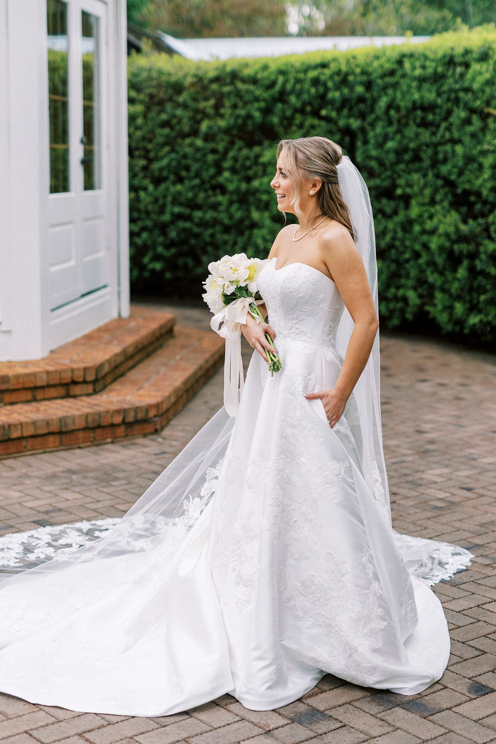 bride stands looking to side holding bouquet of white flowers 