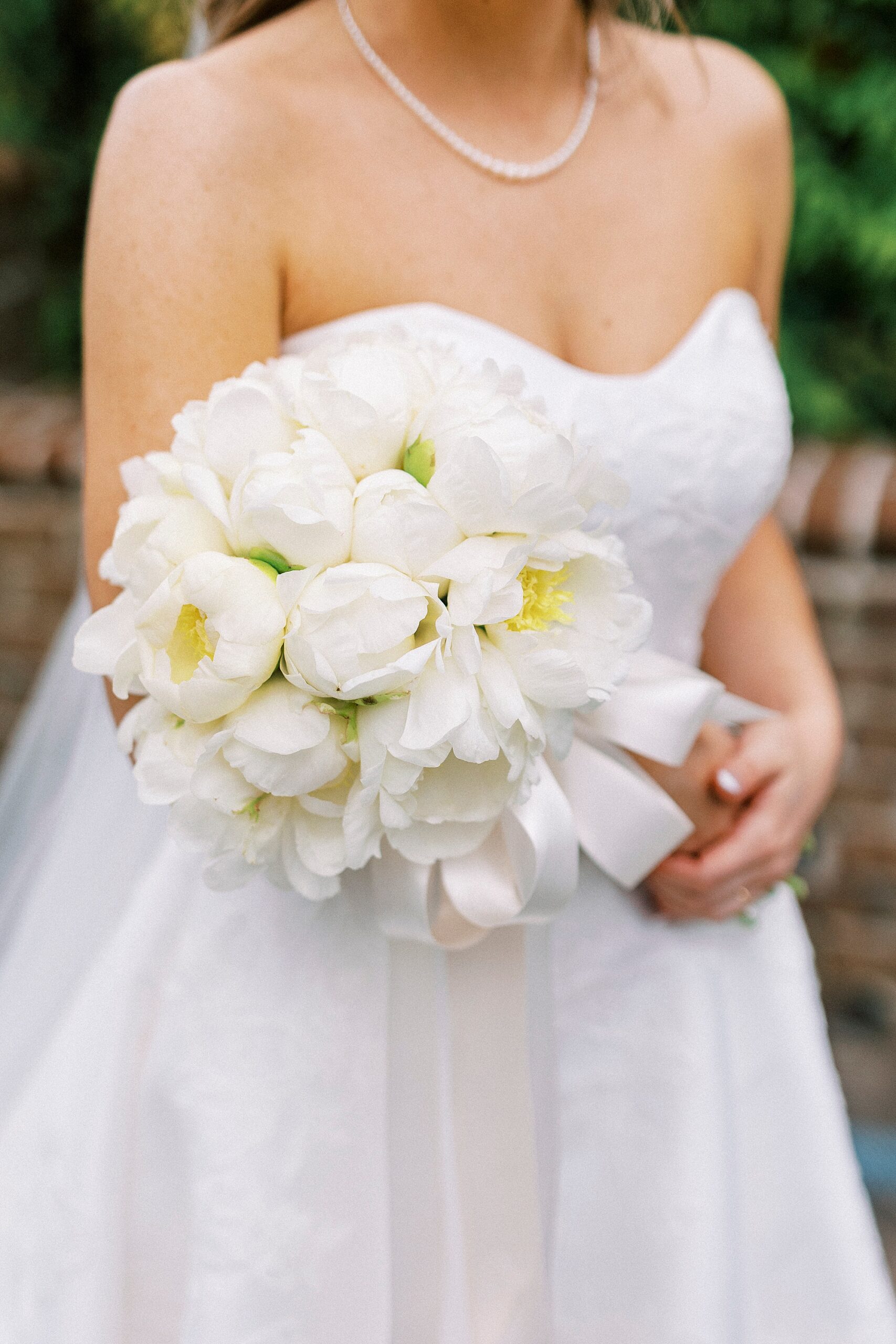 bride holds all white bouquet with white ribbon for spring wedding at the Sutherland