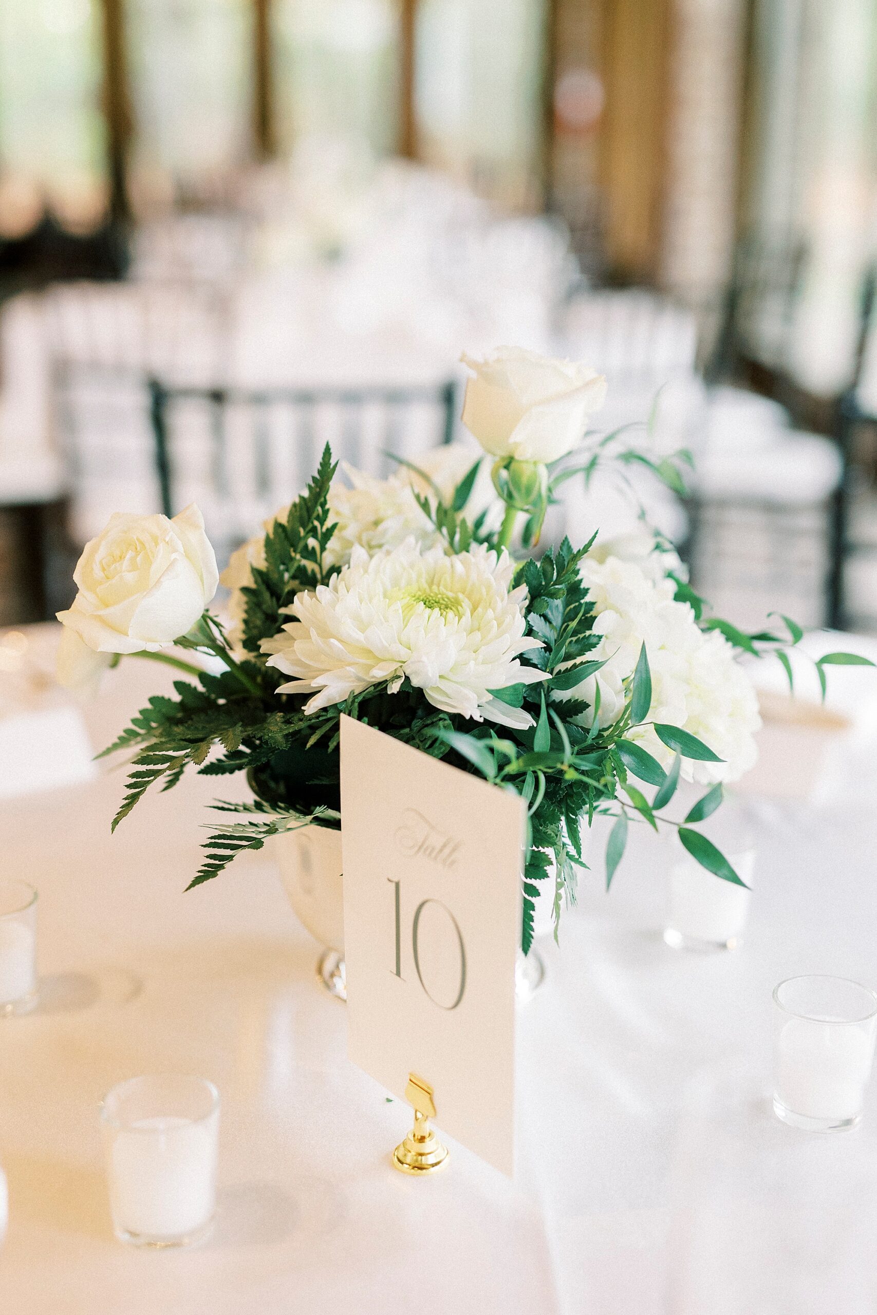 wedding reception centerpiece with white flowers and gold table numbers 