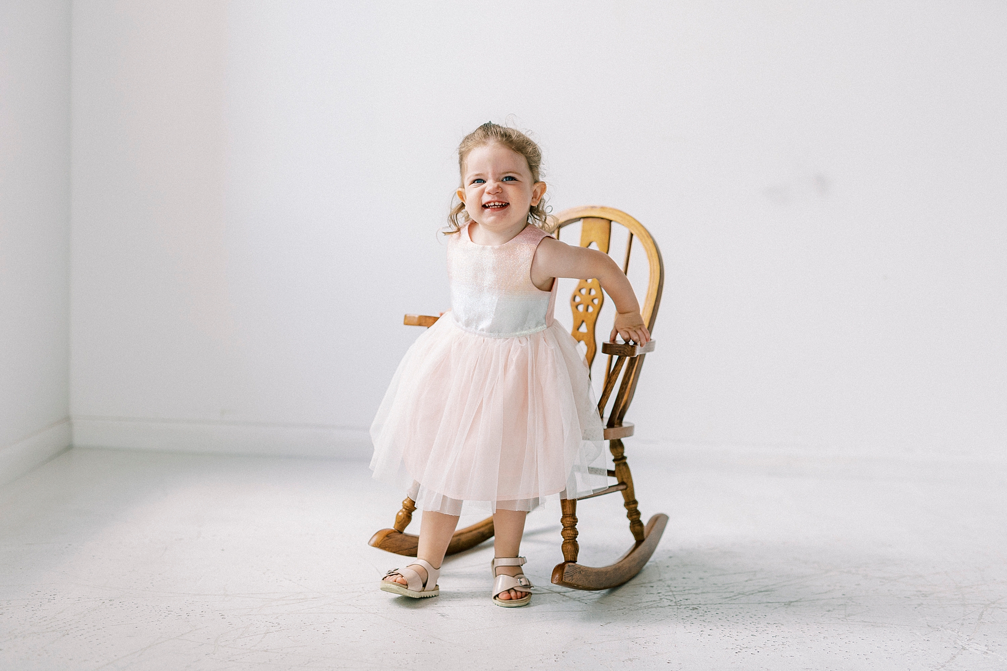 toddler pushes out of rocking chair during Birthday Photos at Charlotte NC Photography Studio