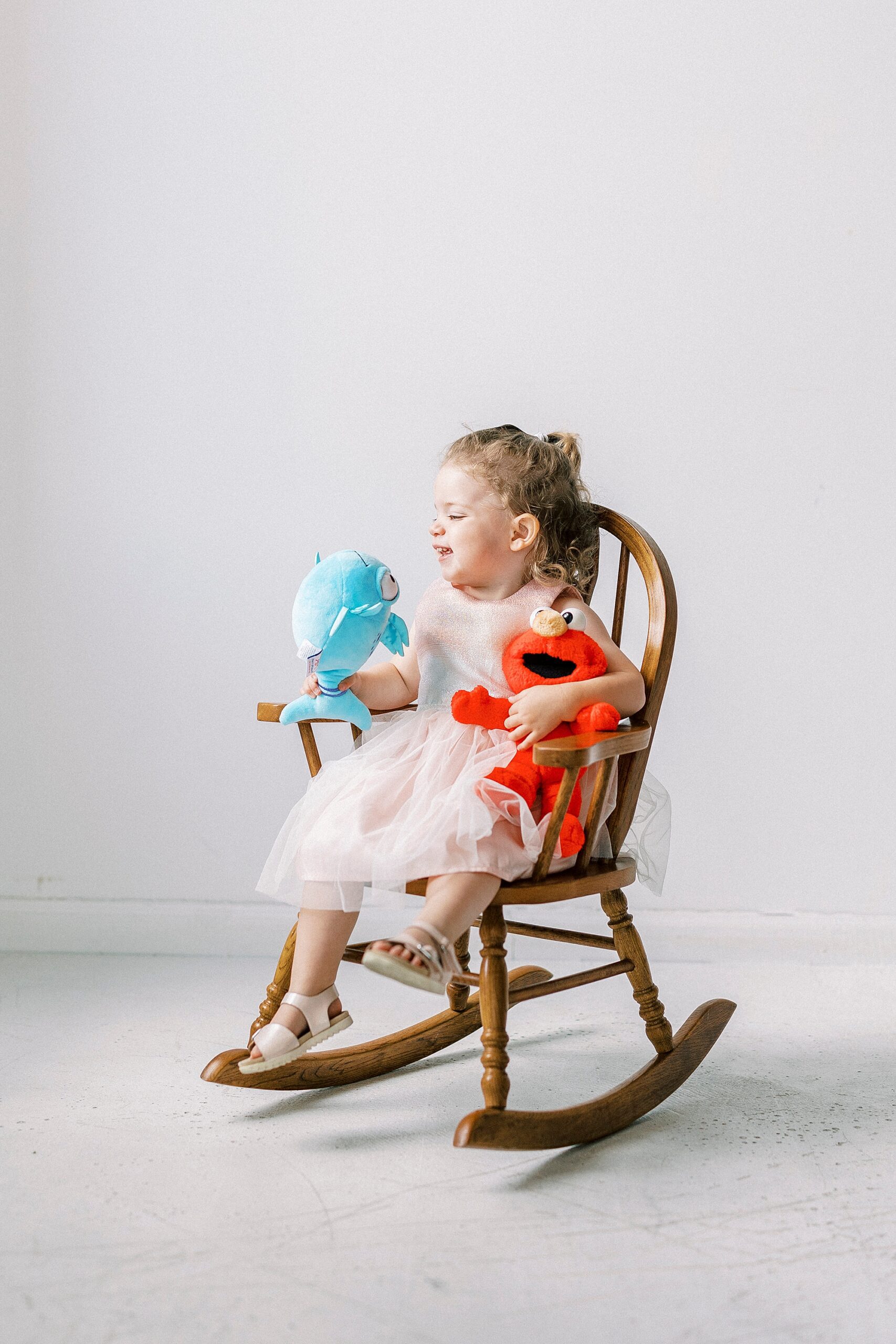 two year old rocks with favorite stuffed animals during studio birthday photos 