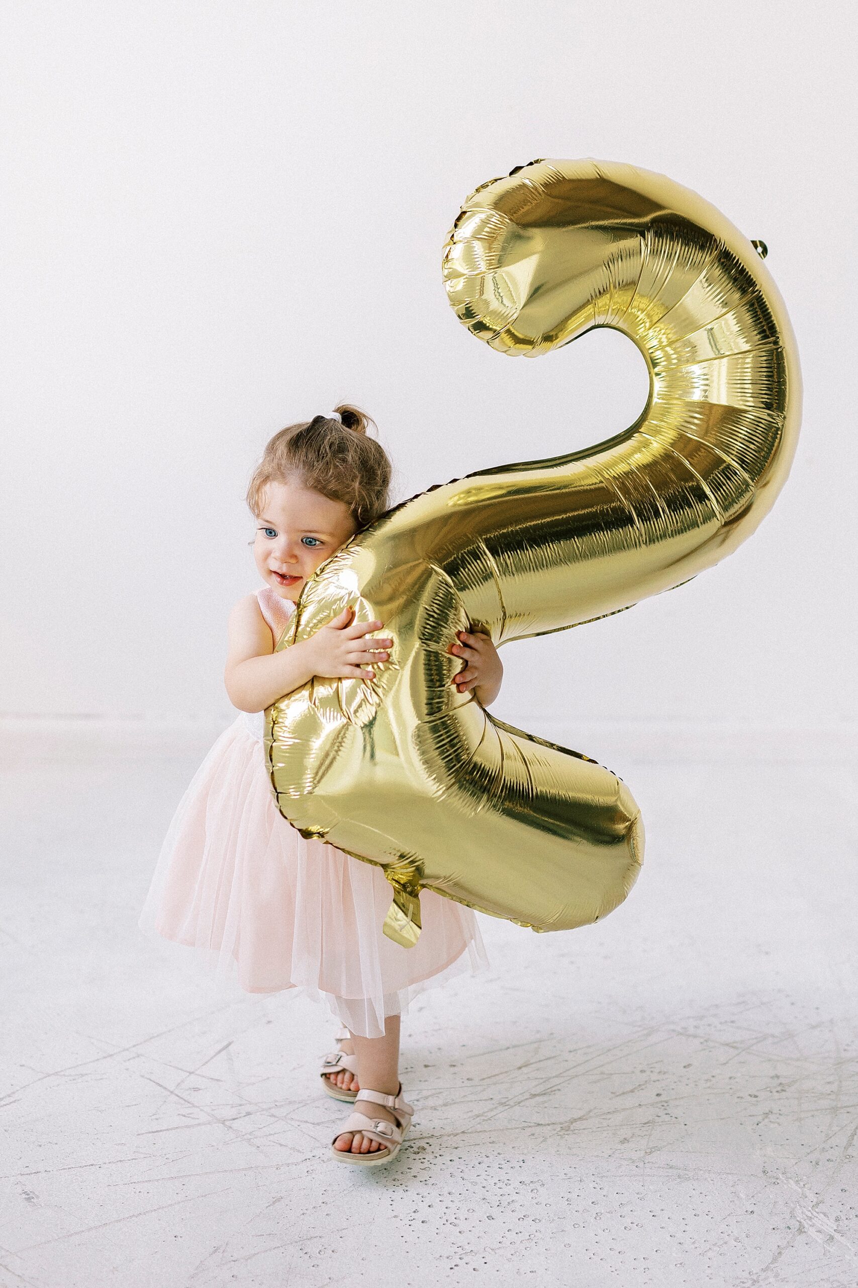 girl hugs gold two balloon in studio 