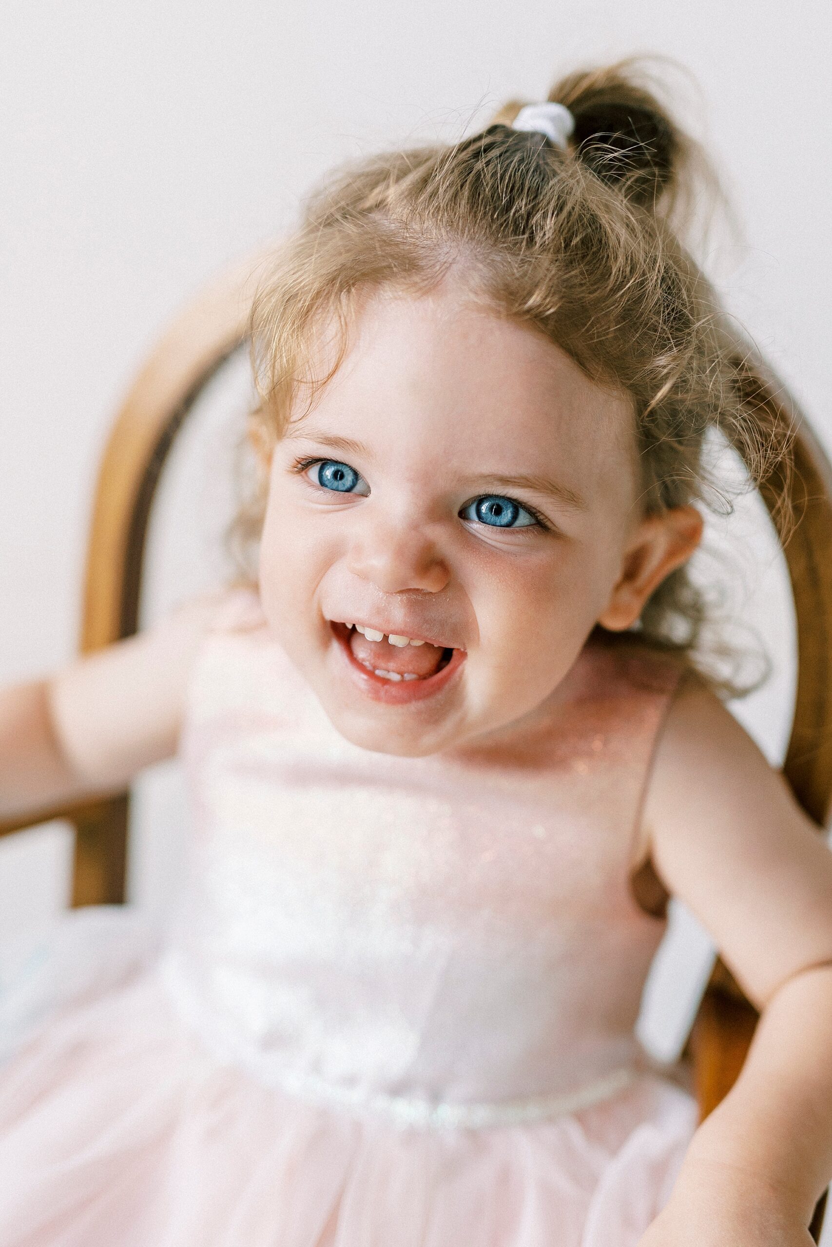 blue eyed girl laughs in rocking chair during Birthday Photos at Charlotte NC Photography Studio