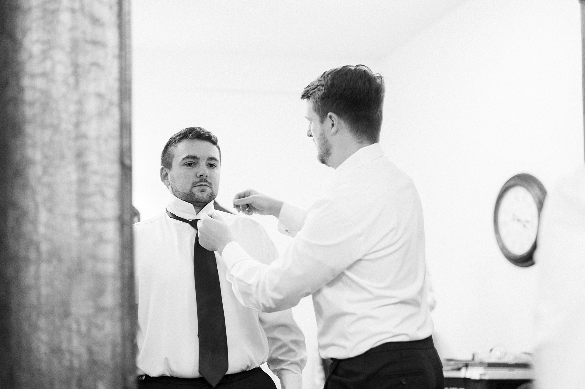 groomsman helps groom with bowtie